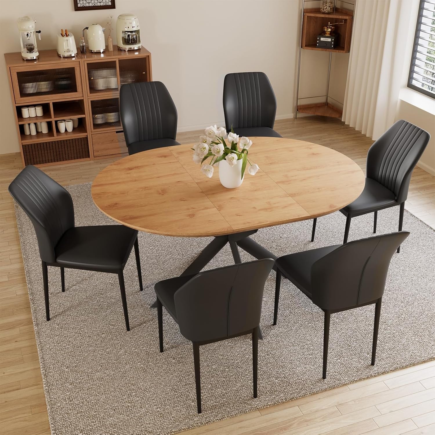 Round oak tabletop with six dark gray/black chairs arranged on a rug in a bright dining room