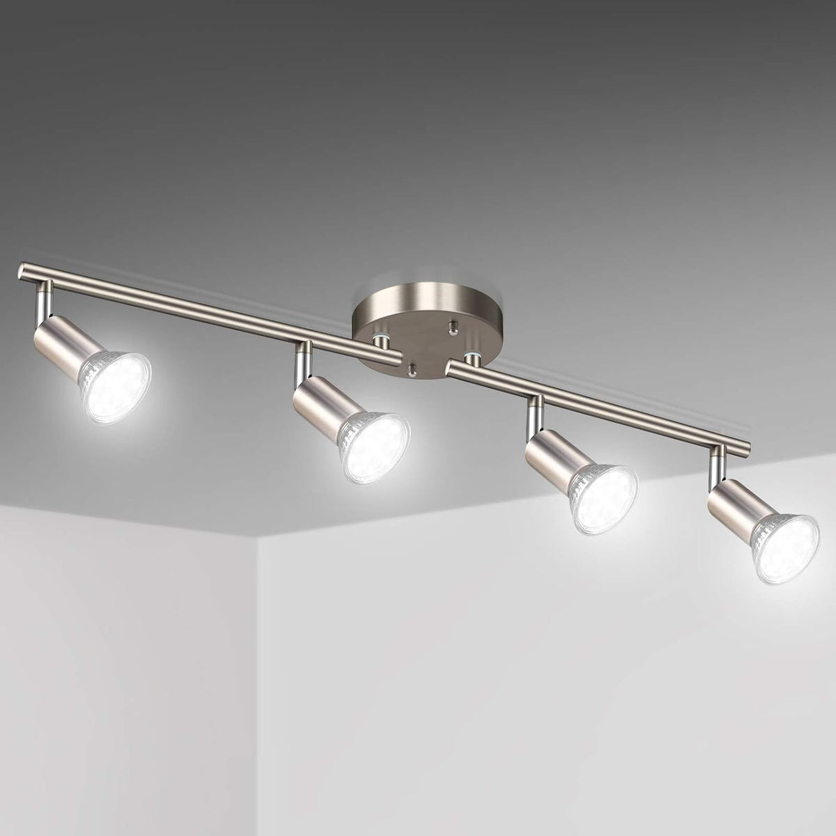 Ceiling-mounted four-light track fixture in brushed nickel, each adjustable head shining downward.