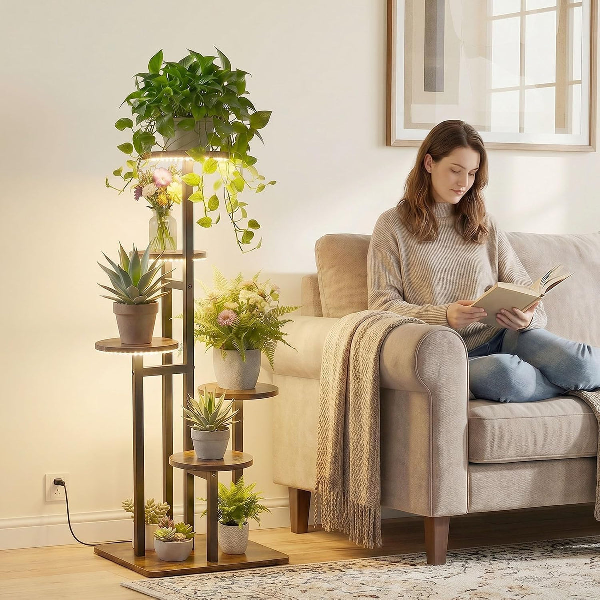 Lit 5-tier plant stand next to a sofa with a woman reading, showing scale and placement in a living room