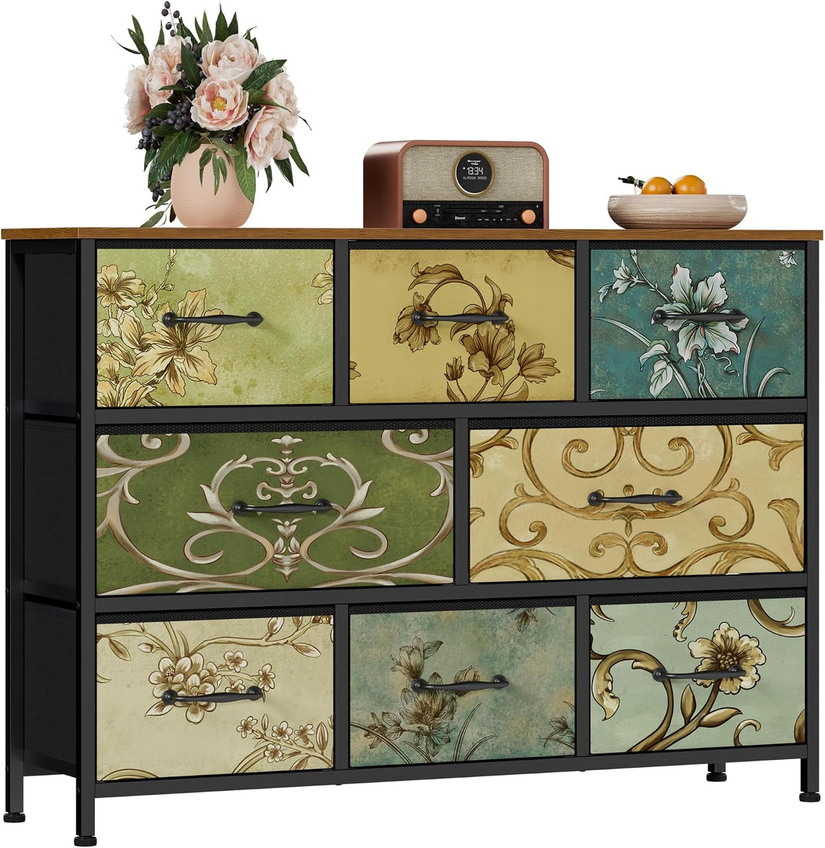 Wider view of a low fabric storage dresser with nine floral-print drawers, black frame and wood top with decor