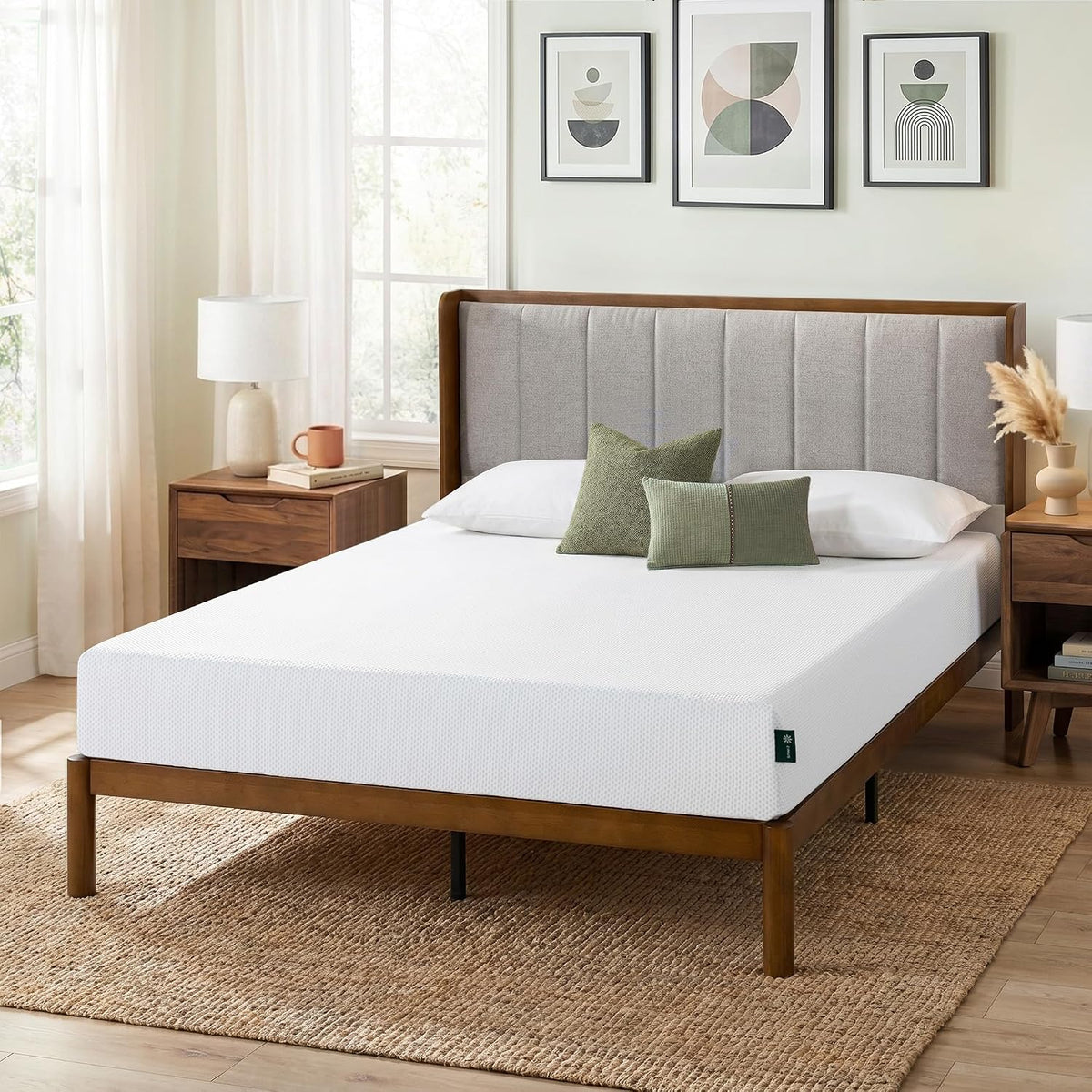 Mattress on a wooden platform bed in a bright bedroom with pillows, nightstands, and framed art above the headboard.