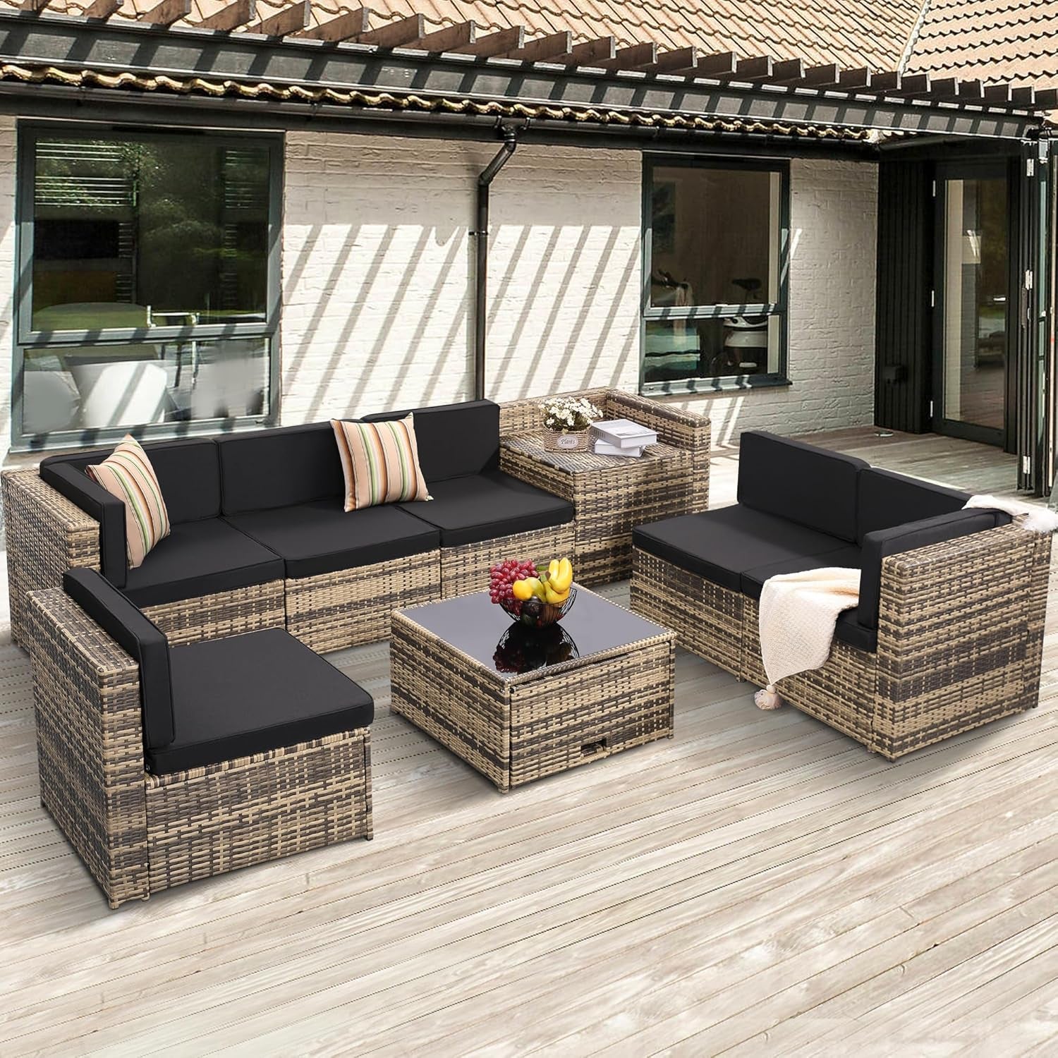 Natural-tone PE rattan patio sectional with black cushions, angled front view on a wood deck