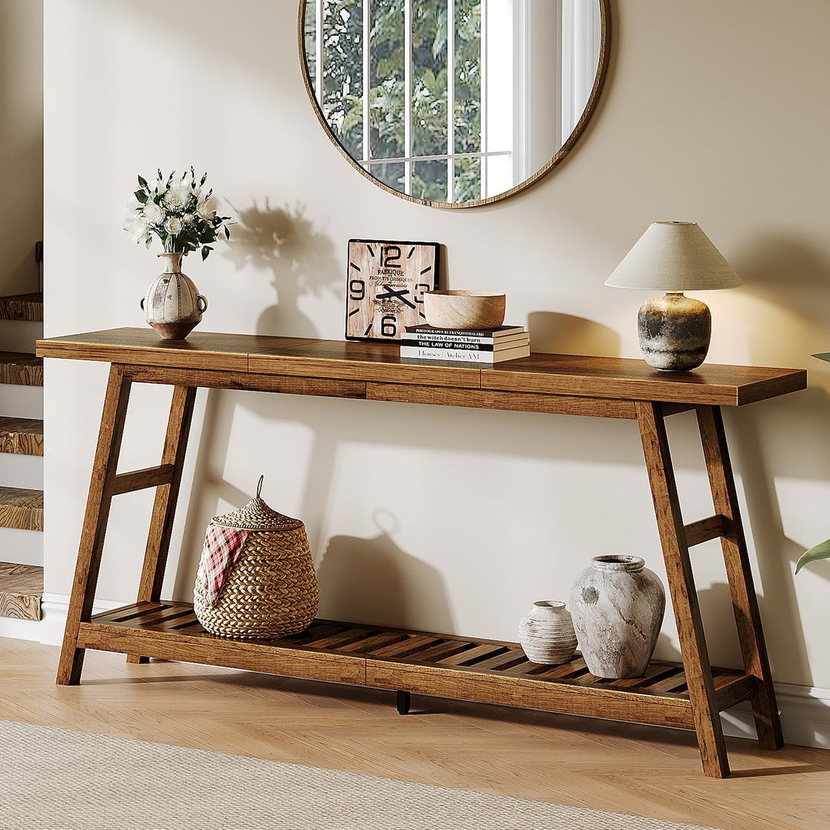 Console table styled under a round mirror with a lamp and decorative vases on the slatted lower shelf in an entryway