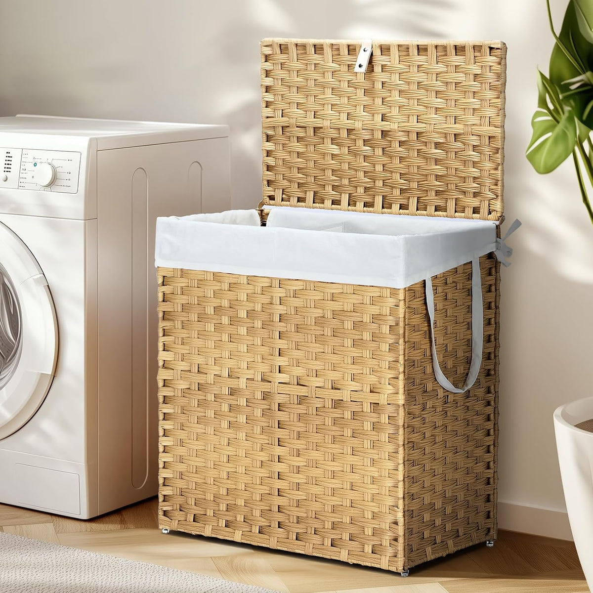 Tall woven rattan laundry hamper with open lid and divided interior beside a washing machine