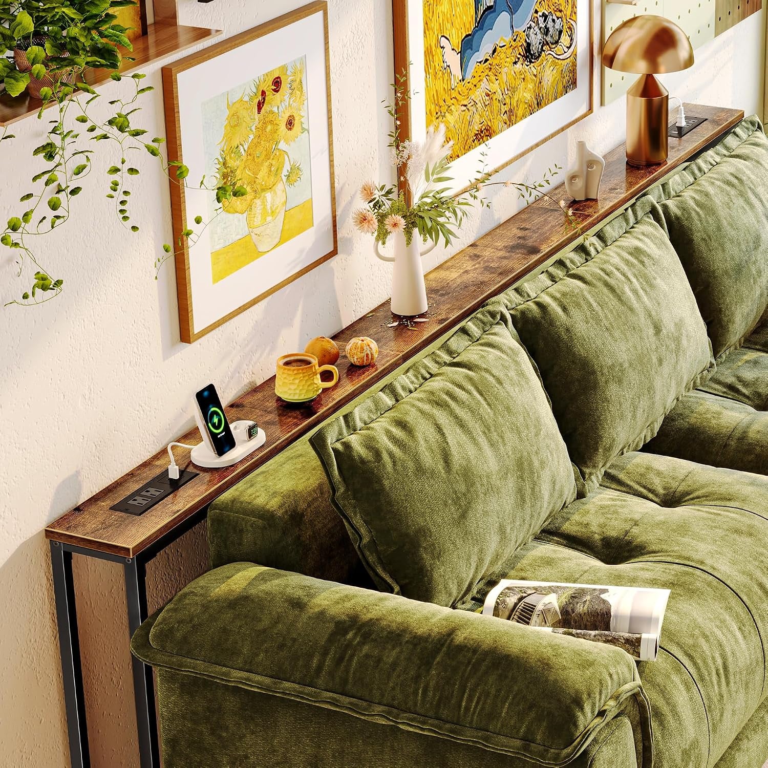 Rustic brown long console table perched behind green couch with lamp, vase and phone charger