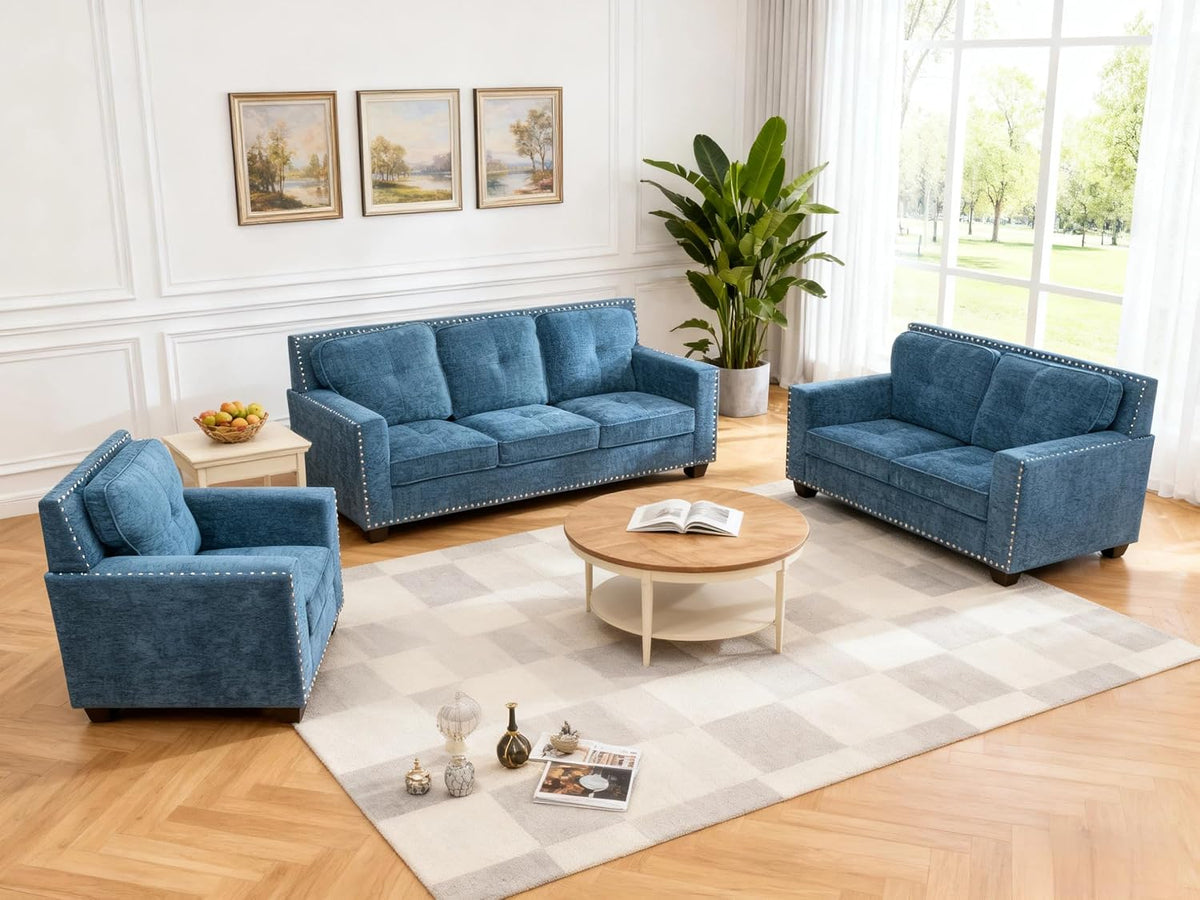 Slightly overhead view of a three-piece blue velvet set arranged around a low round coffee table on a patterned rug.
