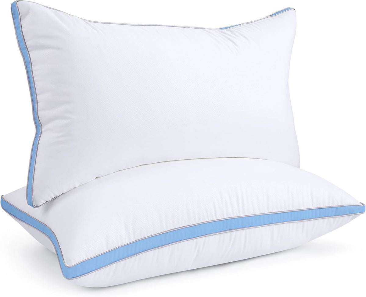 Two white pillows stacked showing a sky-blue piped trim along edges.