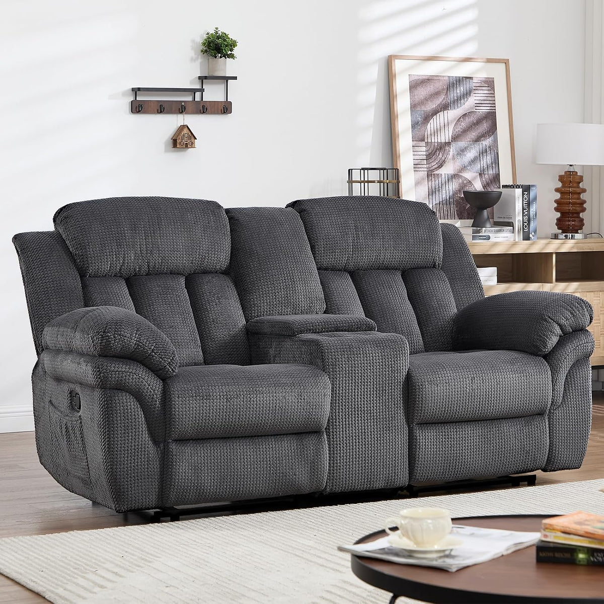 Cropped front three-quarter view of a two-seat reclining loveseat with center console in a staged living room.