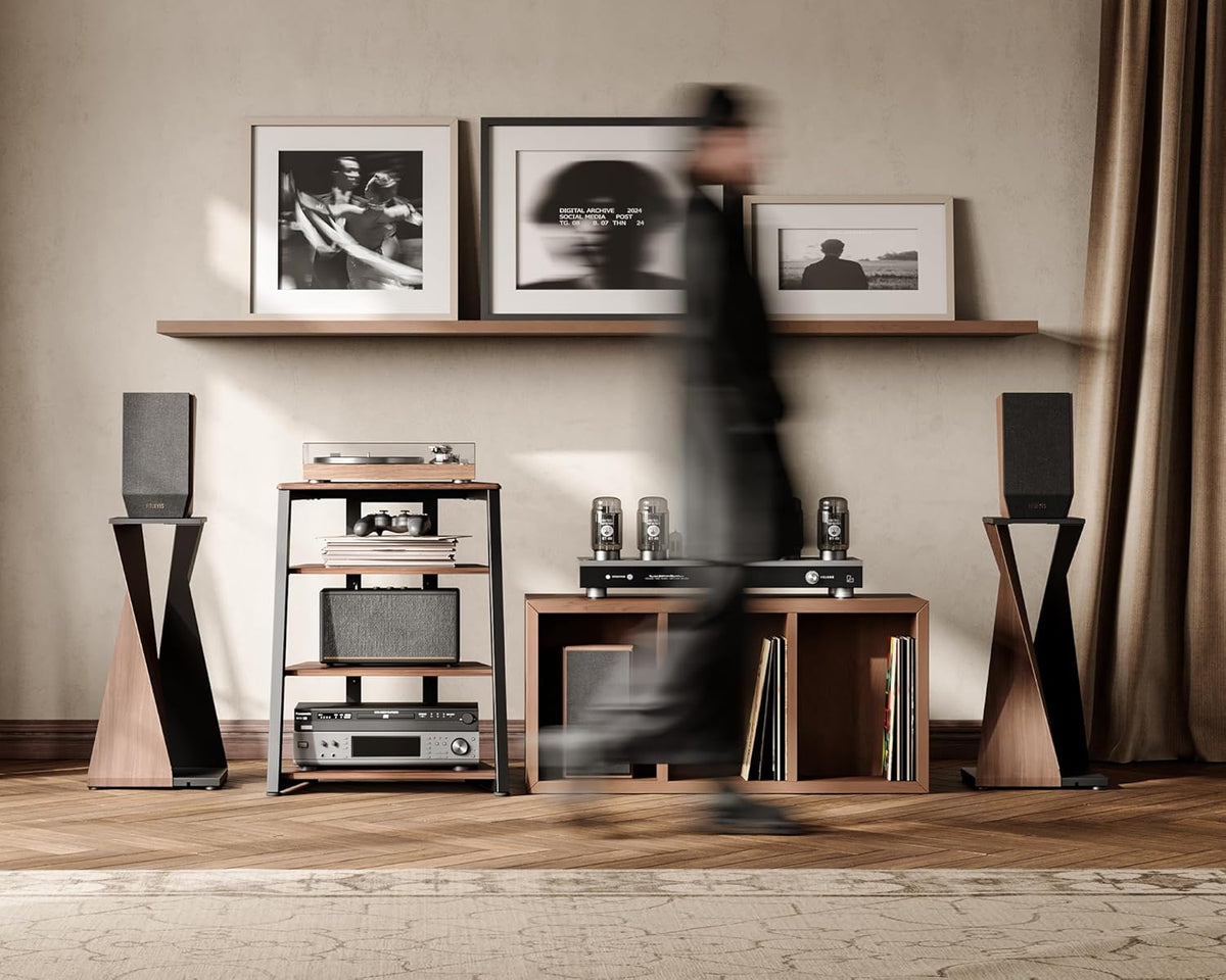 Walnut media stand under a floating shelf, blurred person walking past between speaker pedestals