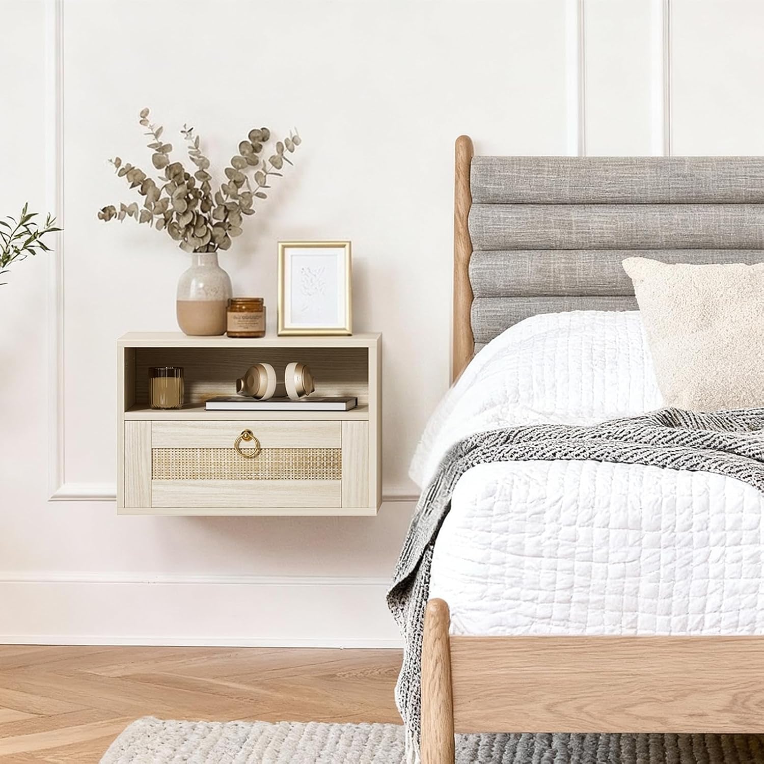 Side view of the wall-mounted nightstand next to a gray upholstered headboard with headphones and framed art on the tabletop