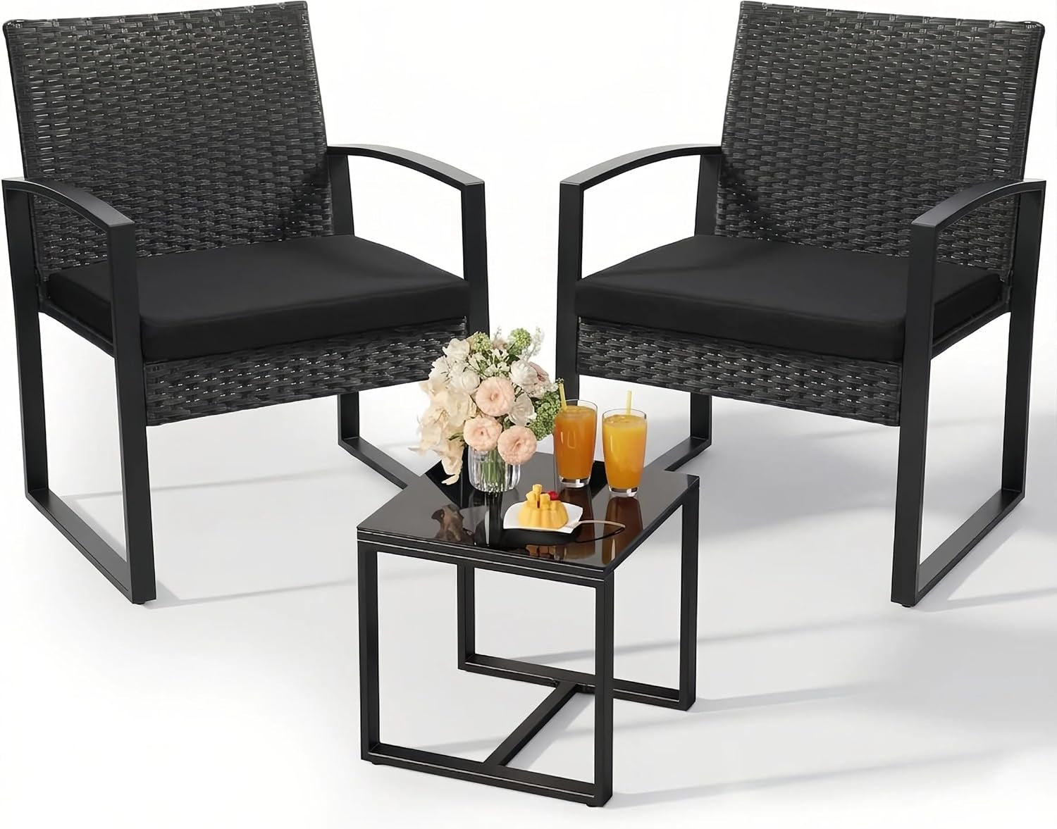 Two black-rattan armchairs with black seat cushions and a small black glass-top side table with drinks