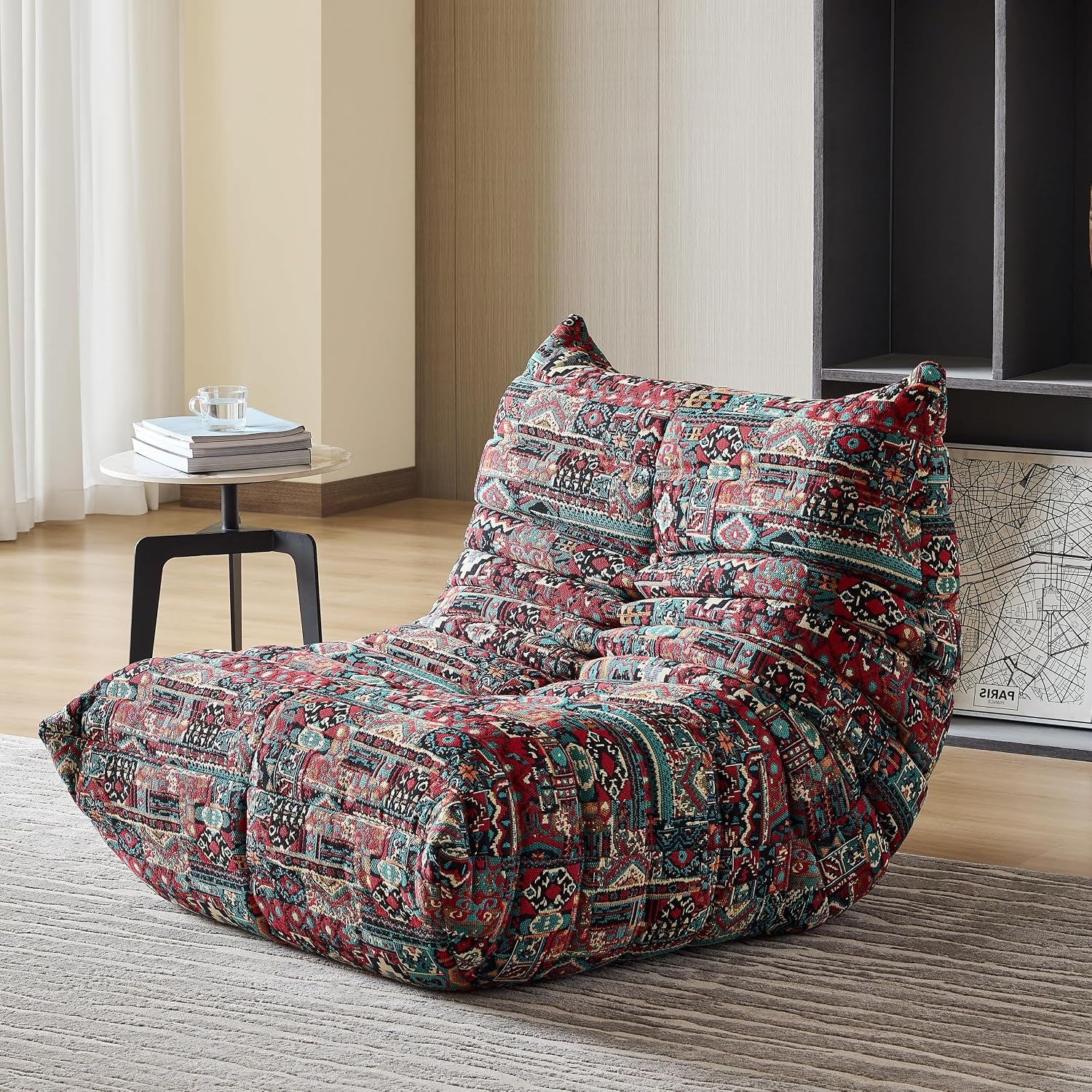Single lounge chair covered in a red patterned tapestry fabric placed beside a small round side table.