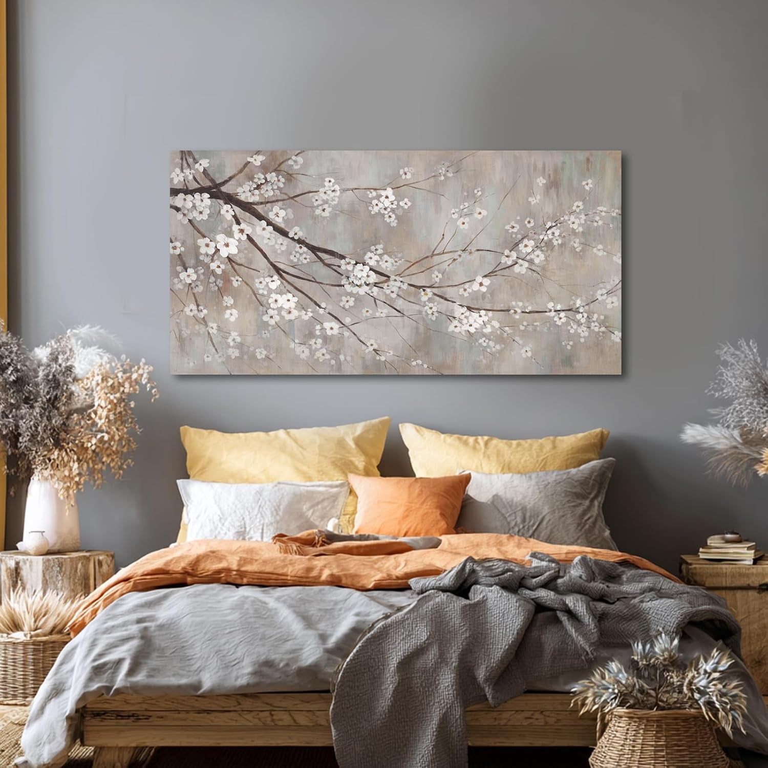 Plum blossom canvas art centered above a bed with layered pillows in a bedroom.