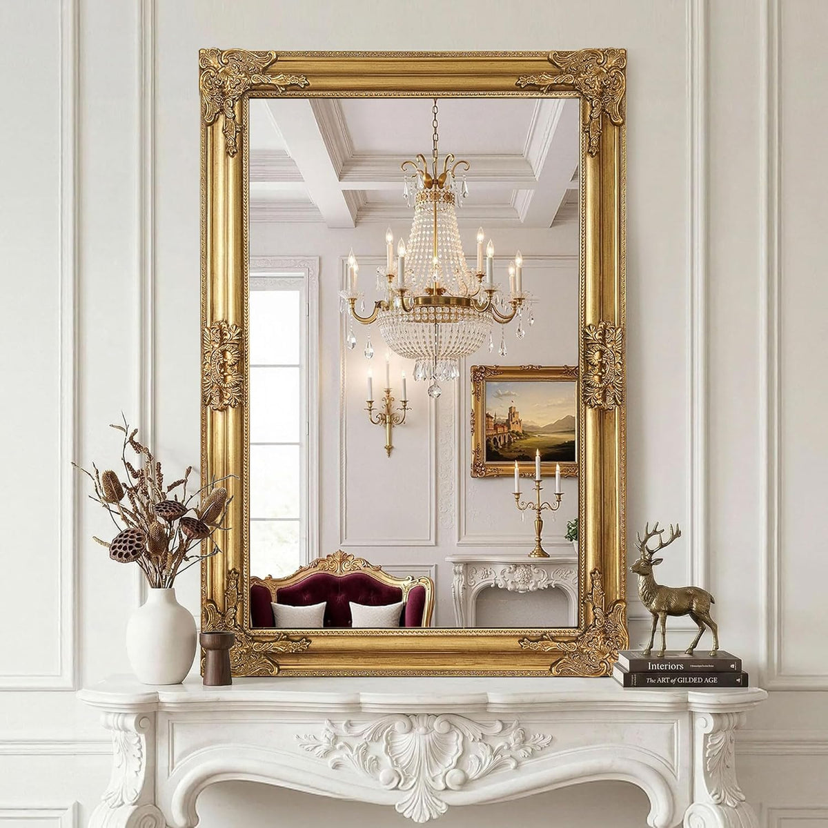 Gold ornate baroque rectangular mirror hung above a white carved mantel reflecting a crystal chandelier