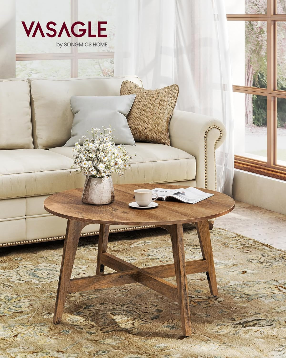 Honey brown round coffee table styled beside a cream sofa on a patterned rug, front-right view