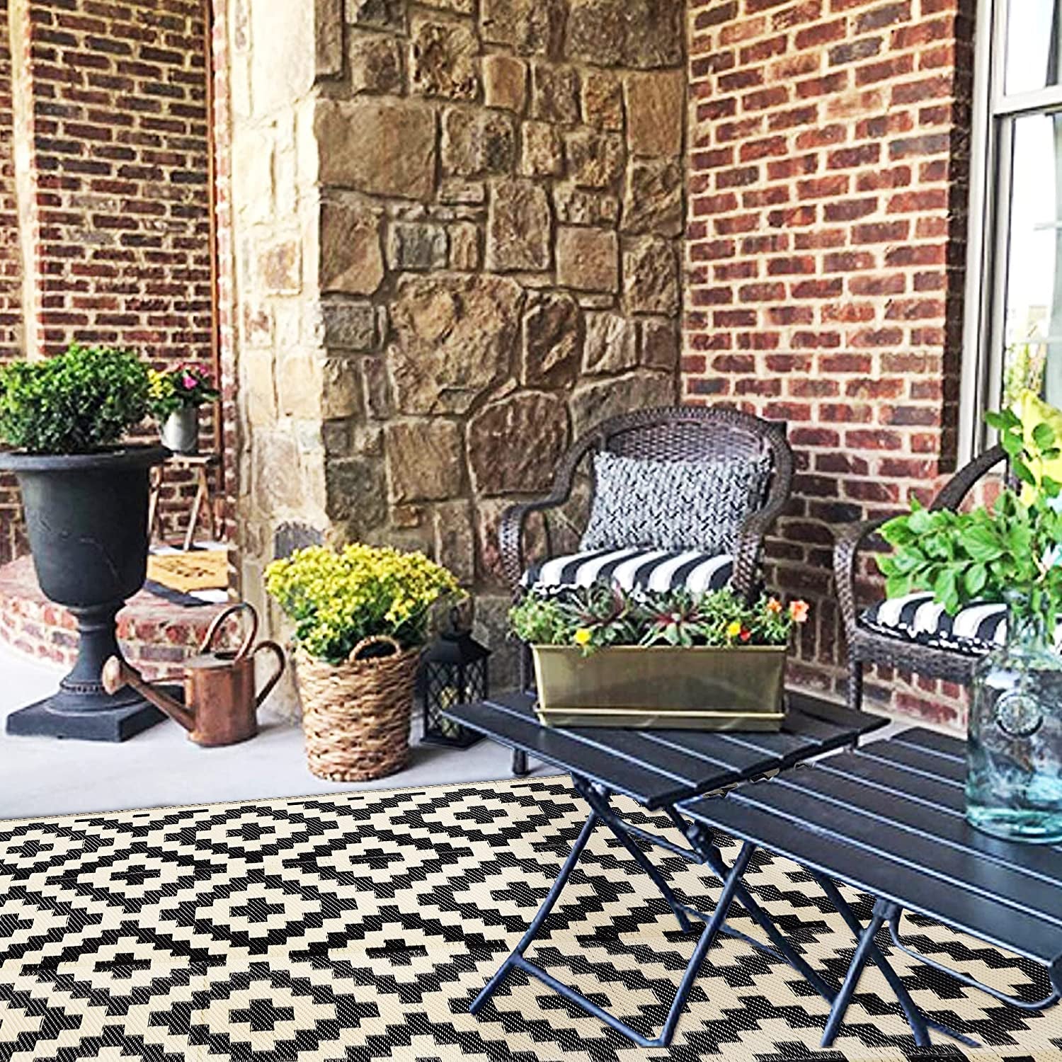 Brick patio with chairs and a metal table on a beige-and-black patterned outdoor rug.