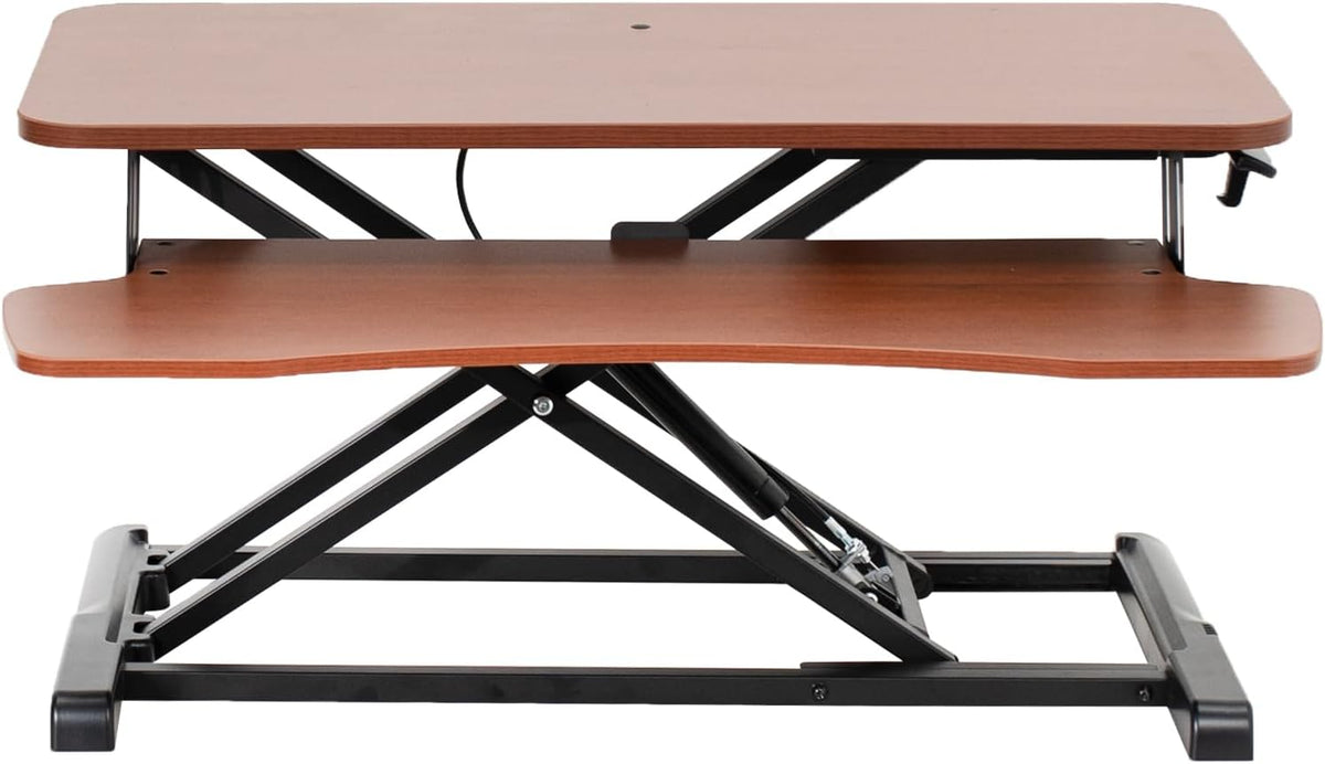 Front-facing view of a cherry wood two-tier standing desk converter with raised top and visible lift frame