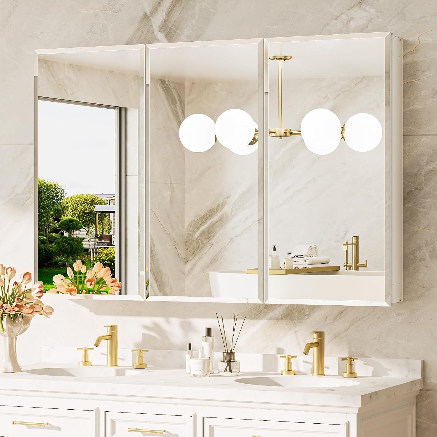 Three mirrored cabinets in a row above double sinks, mirrors reflecting a garden view and globe chandelier