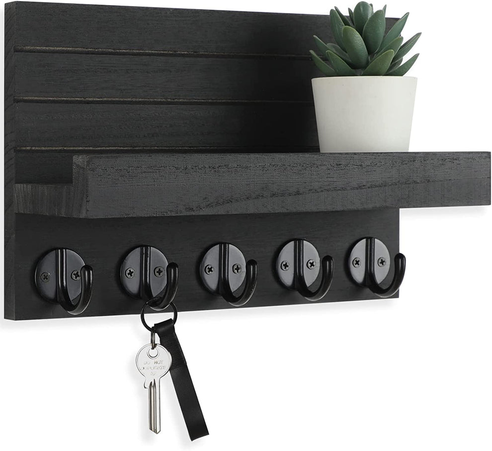 Black paulownia wood wall shelf close-up showing five round metal hooks and shallow display ledge with a small plant
