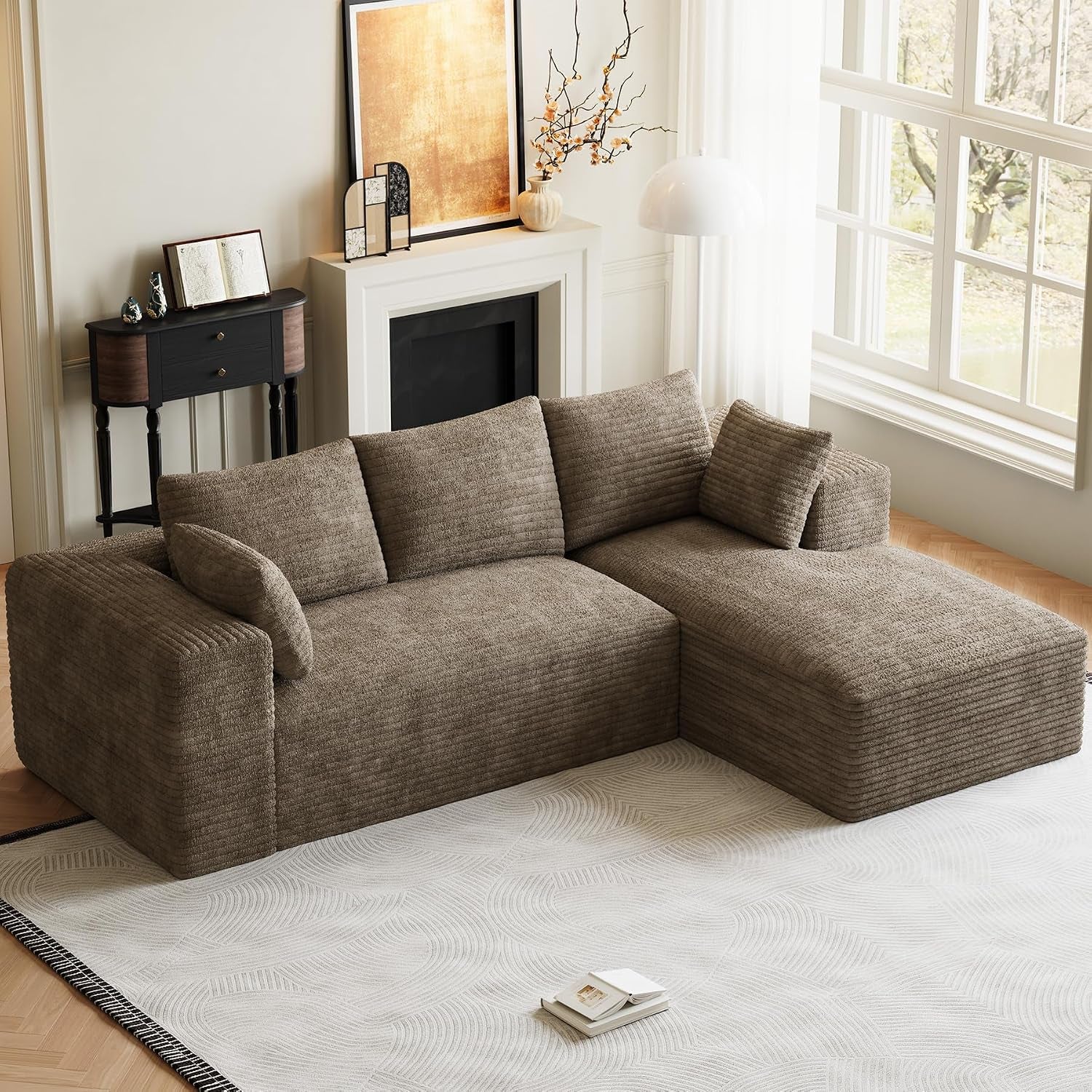 Taupe L-shaped modular sofa with chaise in a sunlit room near a decorated mantel.