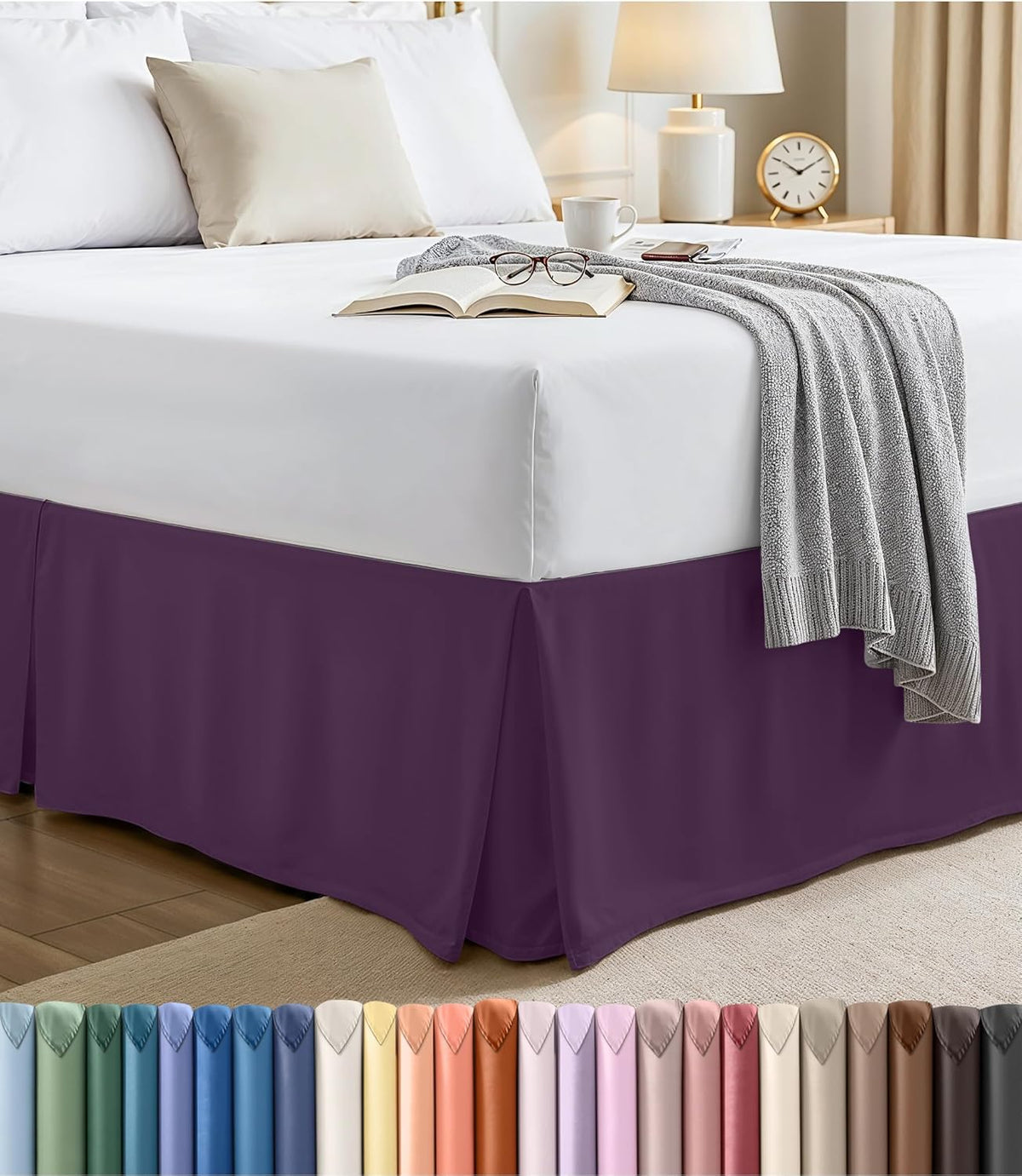 Corner view of a bed with a deep purple pleated bed skirt and a light gray blanket cascading over the edge