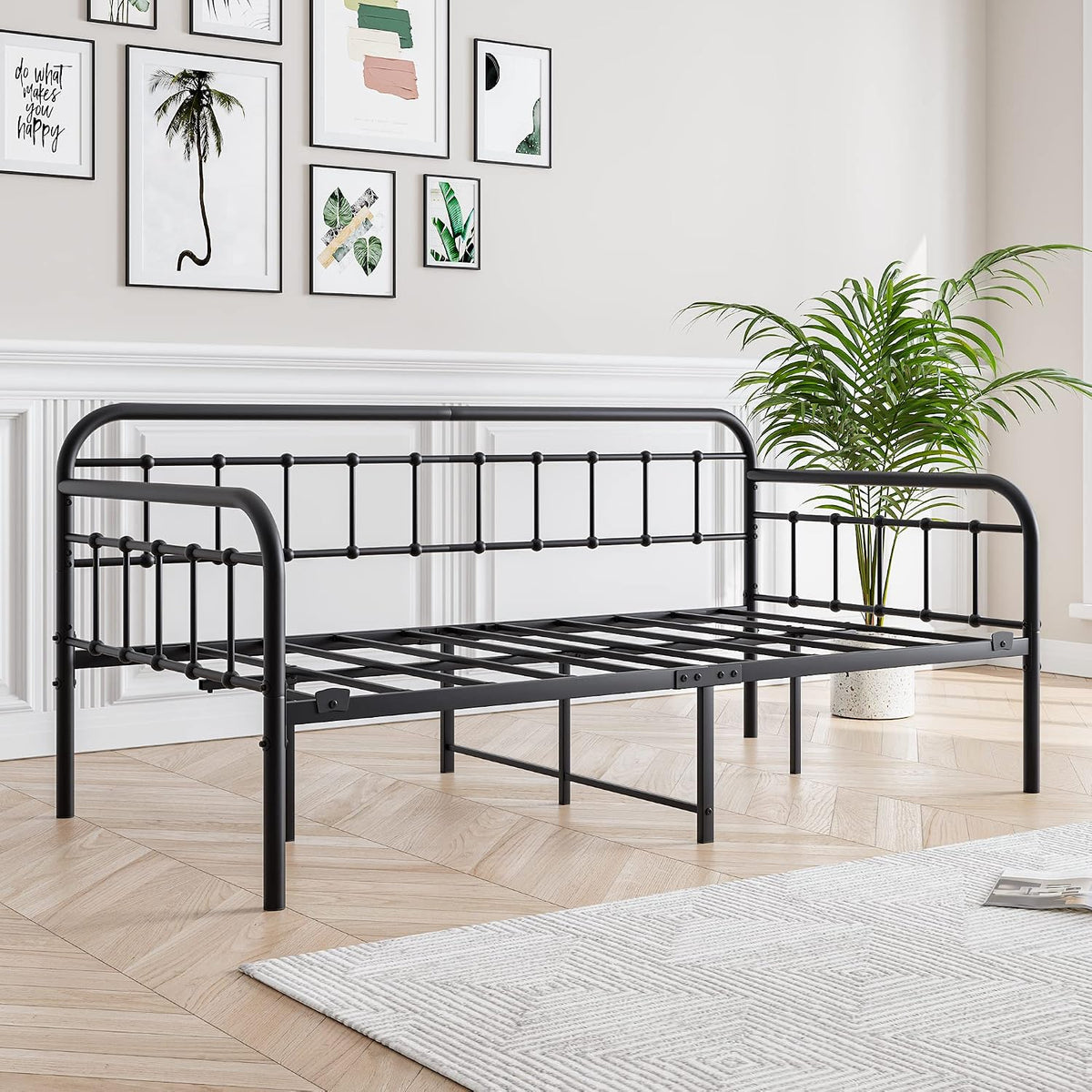 Side-angle of black metal daybed frame without mattress, showing slatted platform and decorative Victorian-style rails.