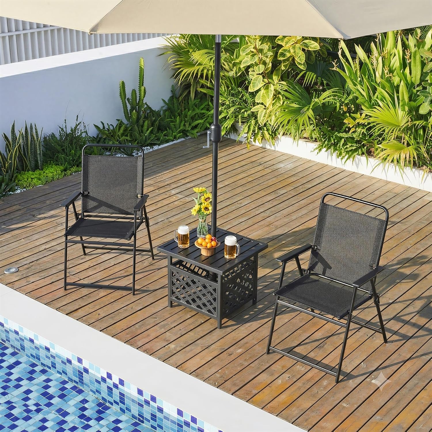 Outdoor deck scene with two black folding mesh chairs flanking a small table under an umbrella by a pool.