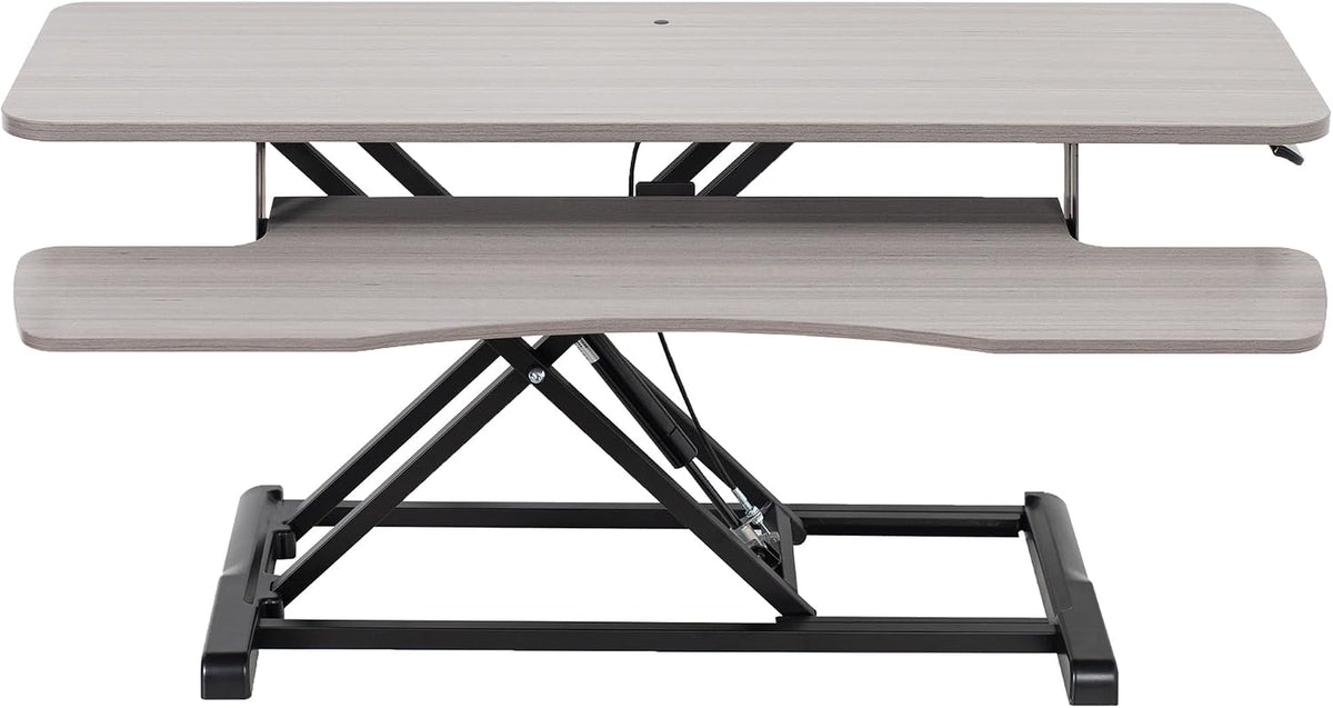 Front view of a light gray wood-finish standing desk converter with black metal X-frame.