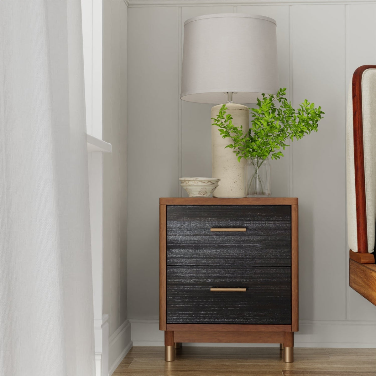 Two-tone walnut and black nightstand styled with a lamp and greenery, front view