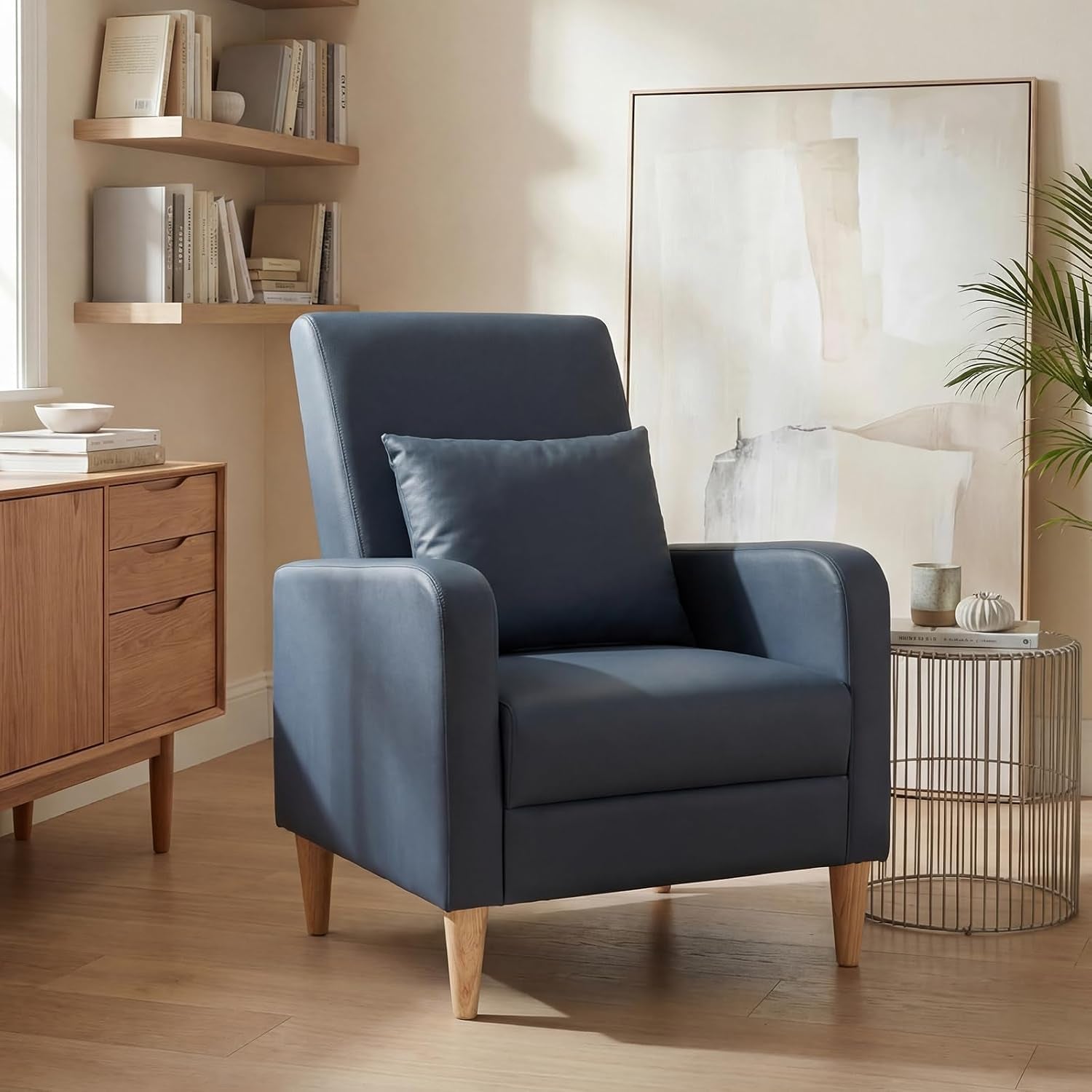 Single deep blue upholstered accent chair with pillow beside a round metal side table