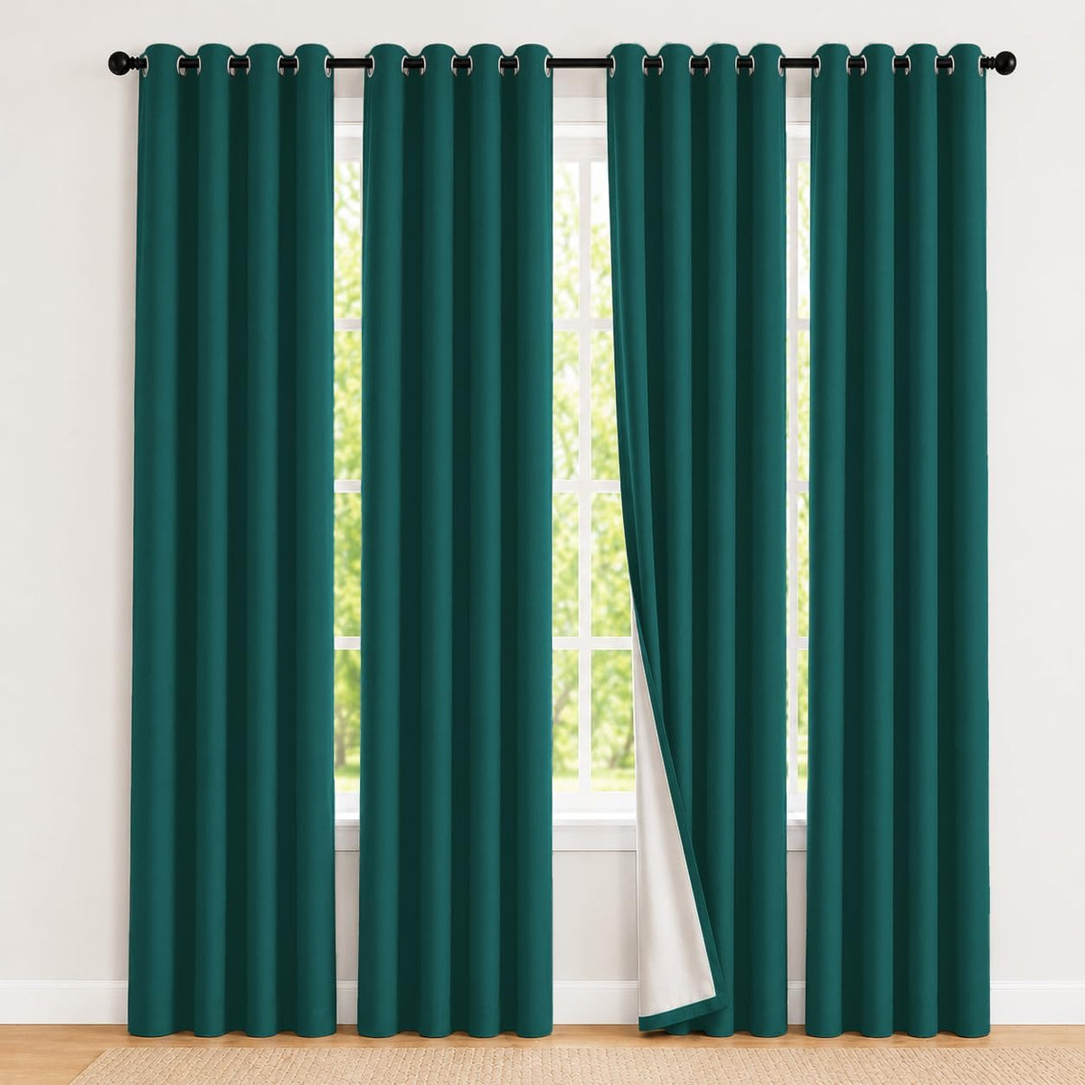 Teal grommet-top curtains hanging full length with one panel slightly pulled to reveal white backing.