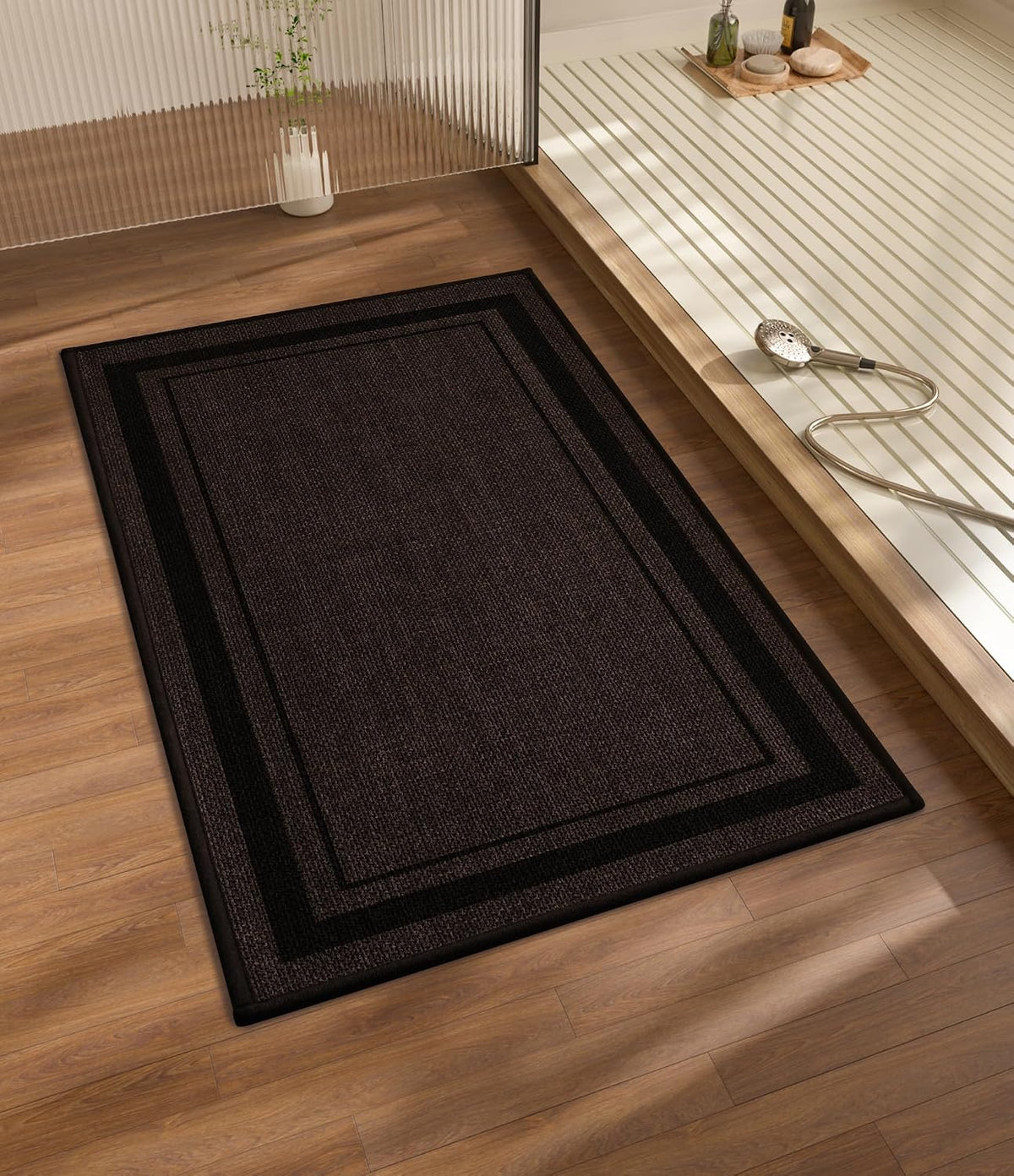 Dark brown rectangular bath mat on wood floor next to a raised shower platform and handheld shower head.