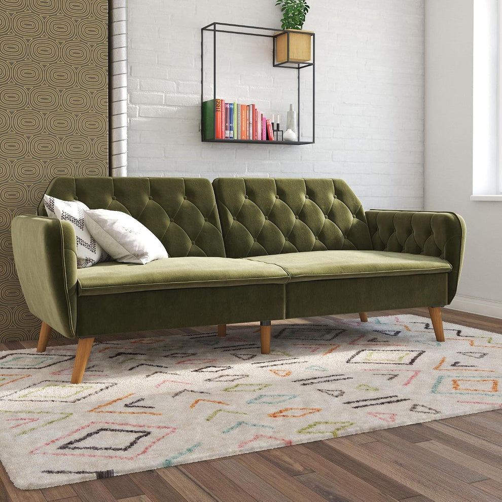 Green velvet tufted futon sofa bed angled front view in a living room setting with patterned rug