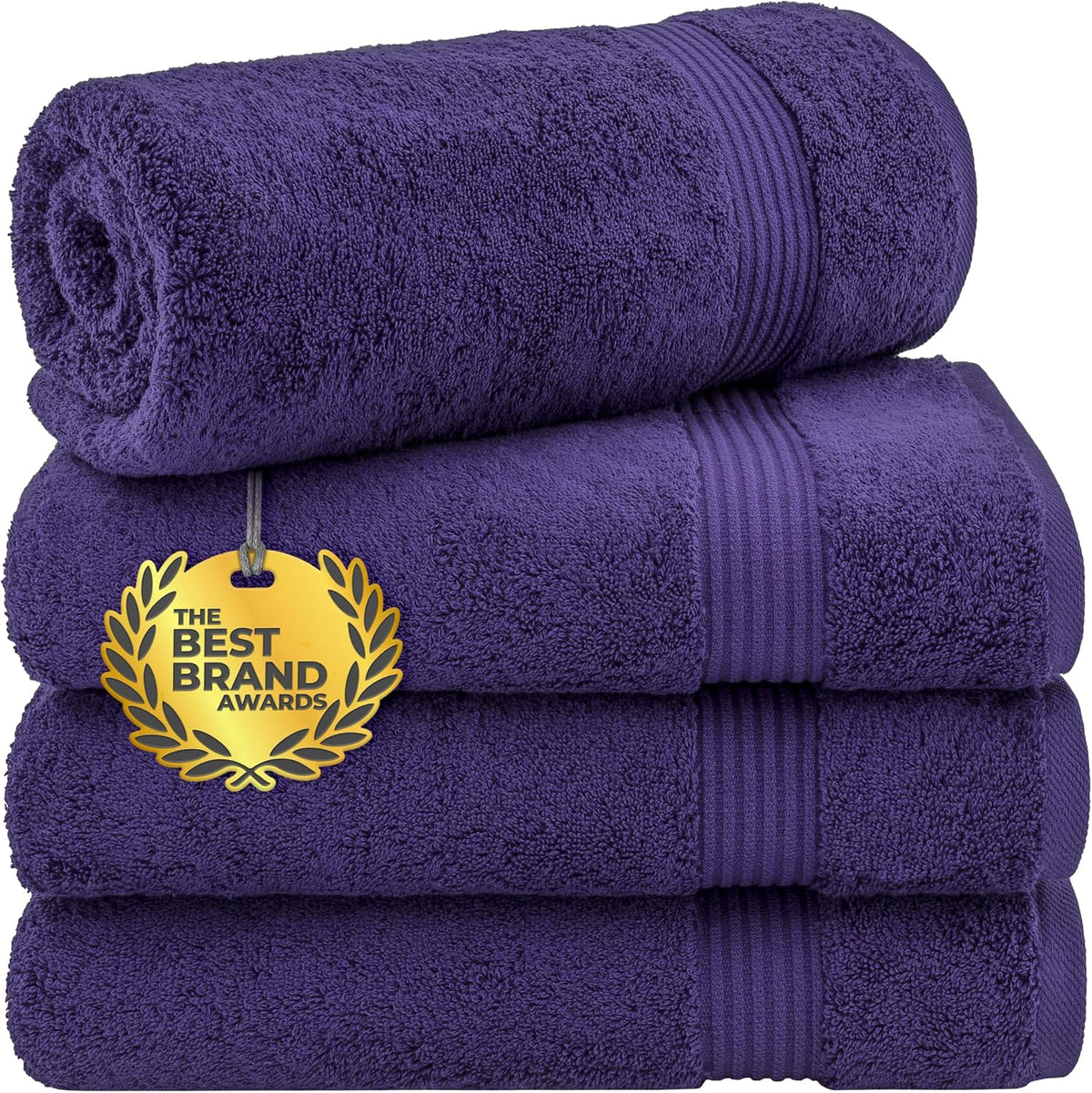 Three deep purple towels stacked with one rolled towel on top, pile texture emphasized