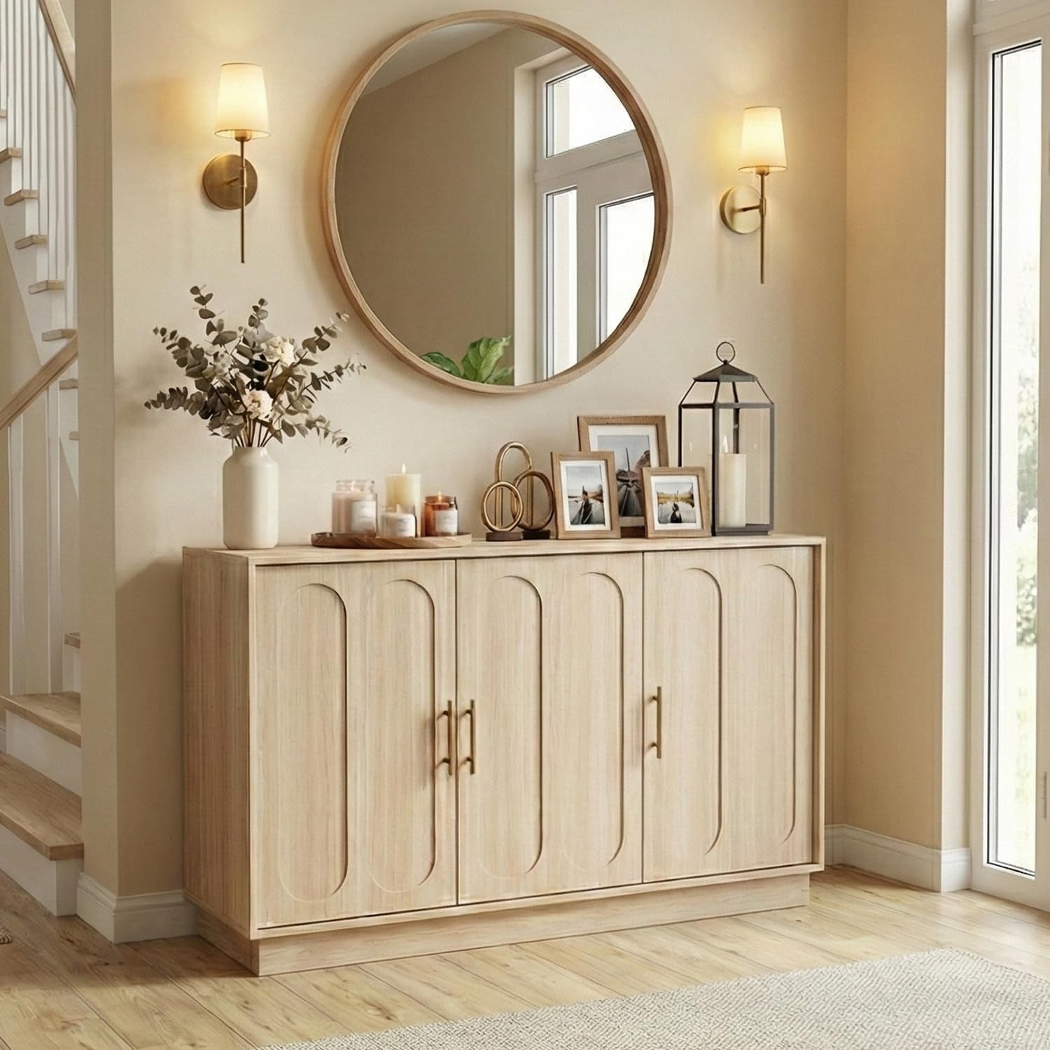 Light wood four‑door fluted sideboard under a round mirror with candles and photos on top