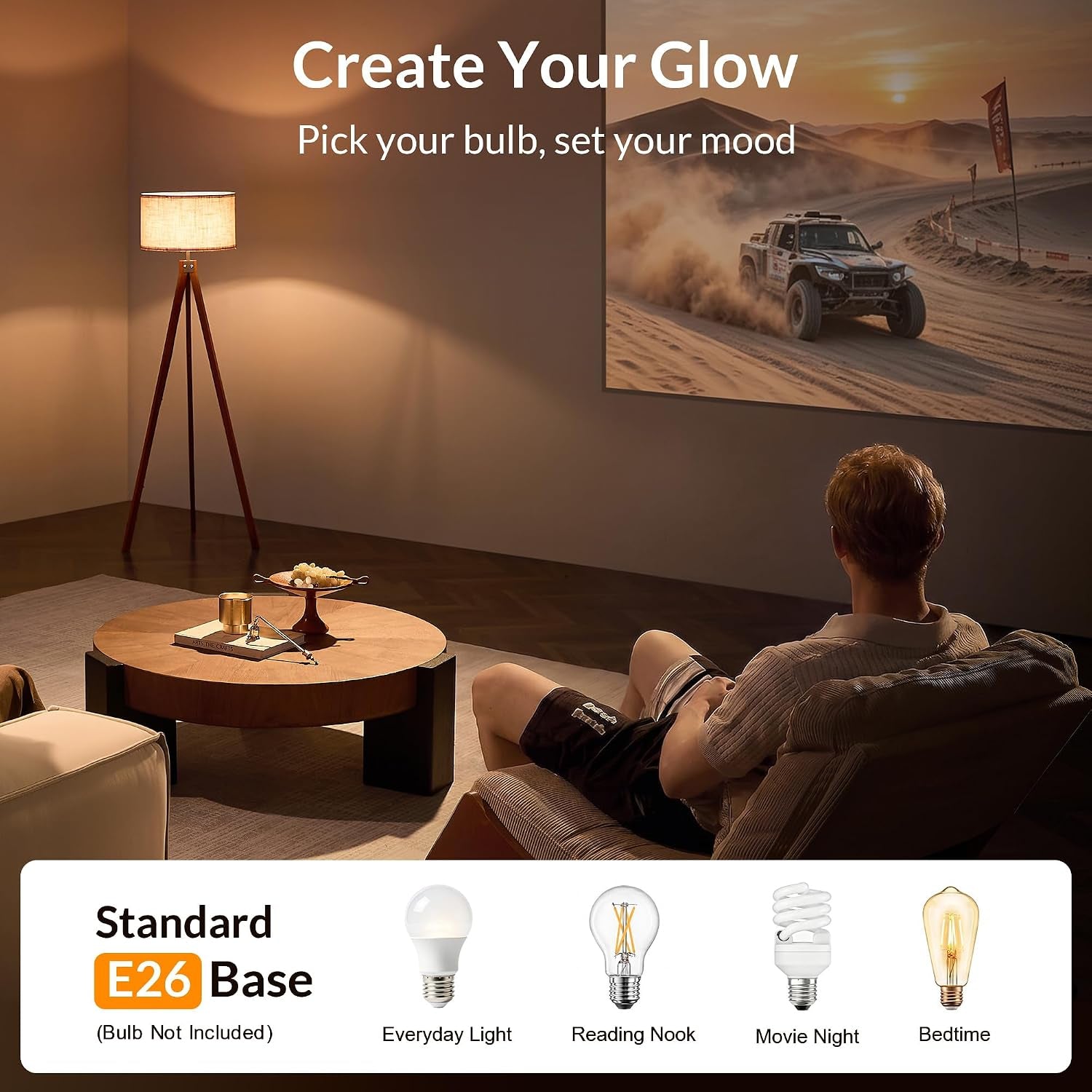 A person reclines in a darkened living room watching a projected scene while a lit tripod floor lamp provides warm ambient