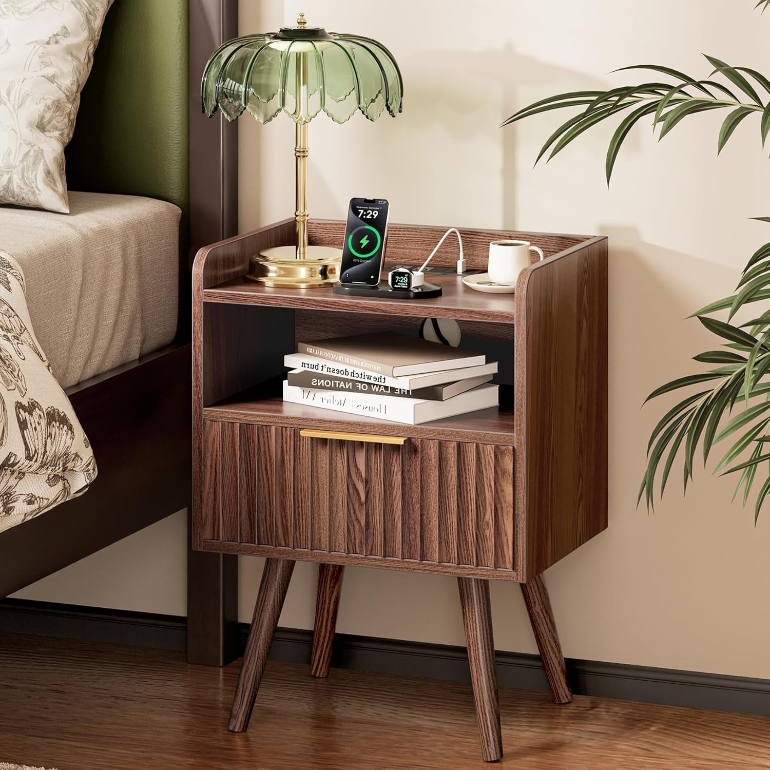 Walnut nightstand beside bed with lamp, phone charging on top and books on middle shelf