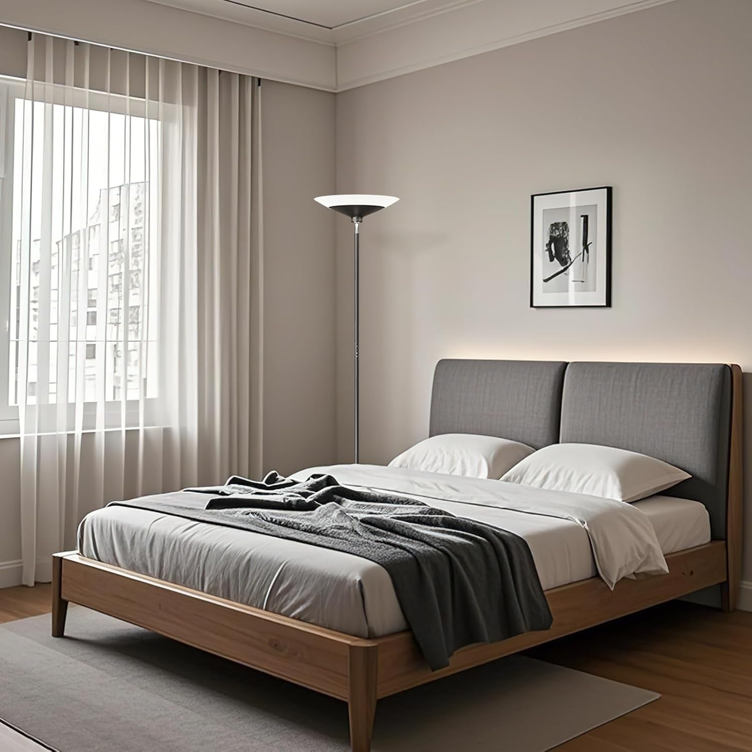 Torchiere floor lamp placed in a bedroom corner beside a low platform bed, showing ambient uplighting.