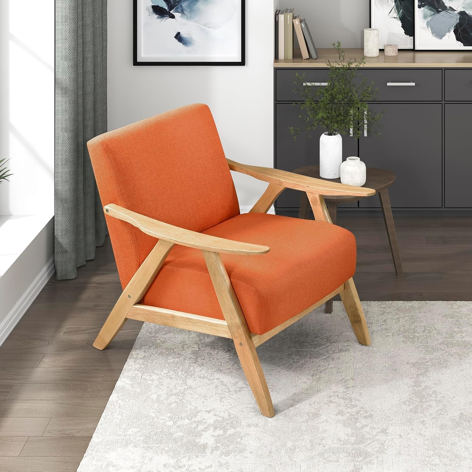 Orange upholstered mid-century accent chair with light wooden frame beside a side table in a living room