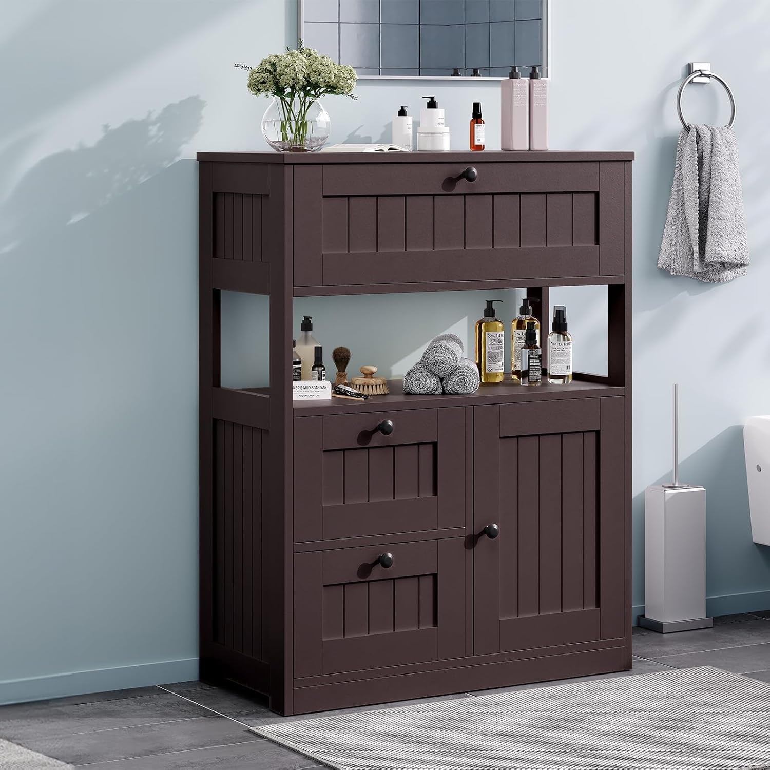 Dark brown cabinet placed against a pale blue wall in a bathroom, styled with towels, bottles and a towel ring nearby