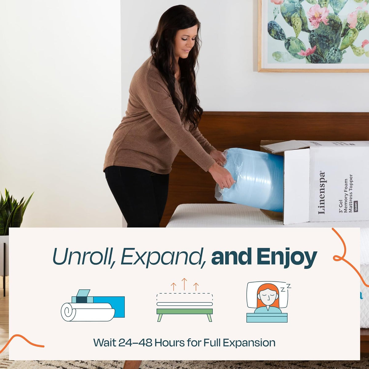 Person removing a rolled, plastic-wrapped blue foam topper from a box at the foot of a bed.