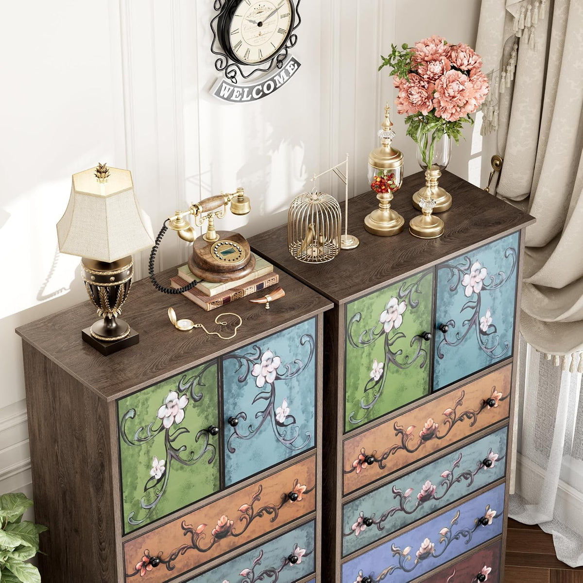 Angled view of the dressers' tops with floral-painted upper doors and styled items: lamp, vintage phone, birdcage and vase.