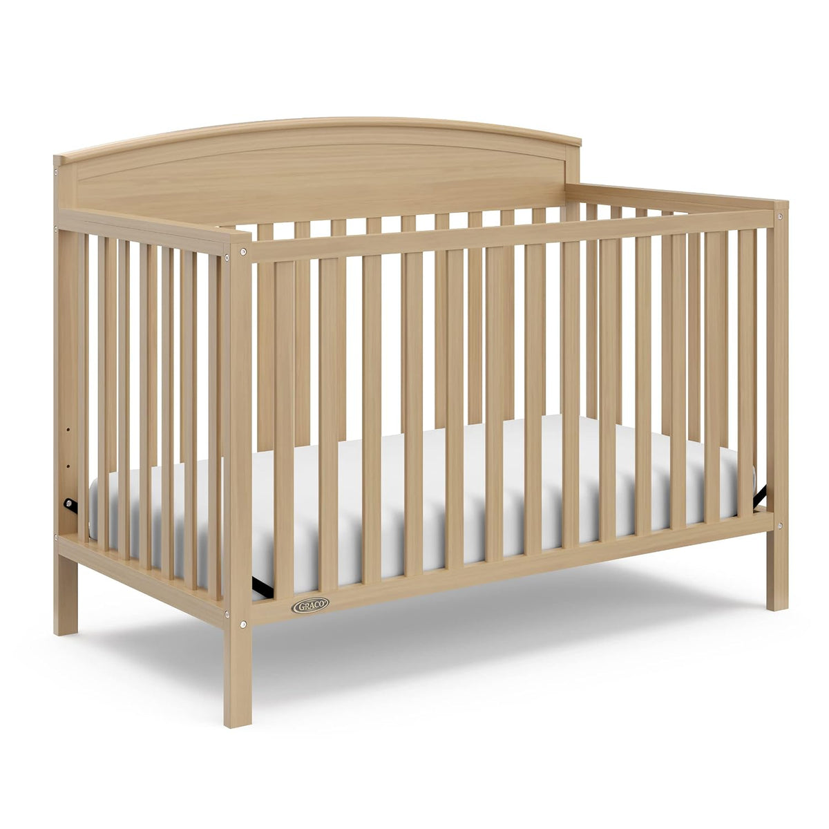 Three-quarter view of a natural wood convertible crib with slatted sides and a white mattress inside