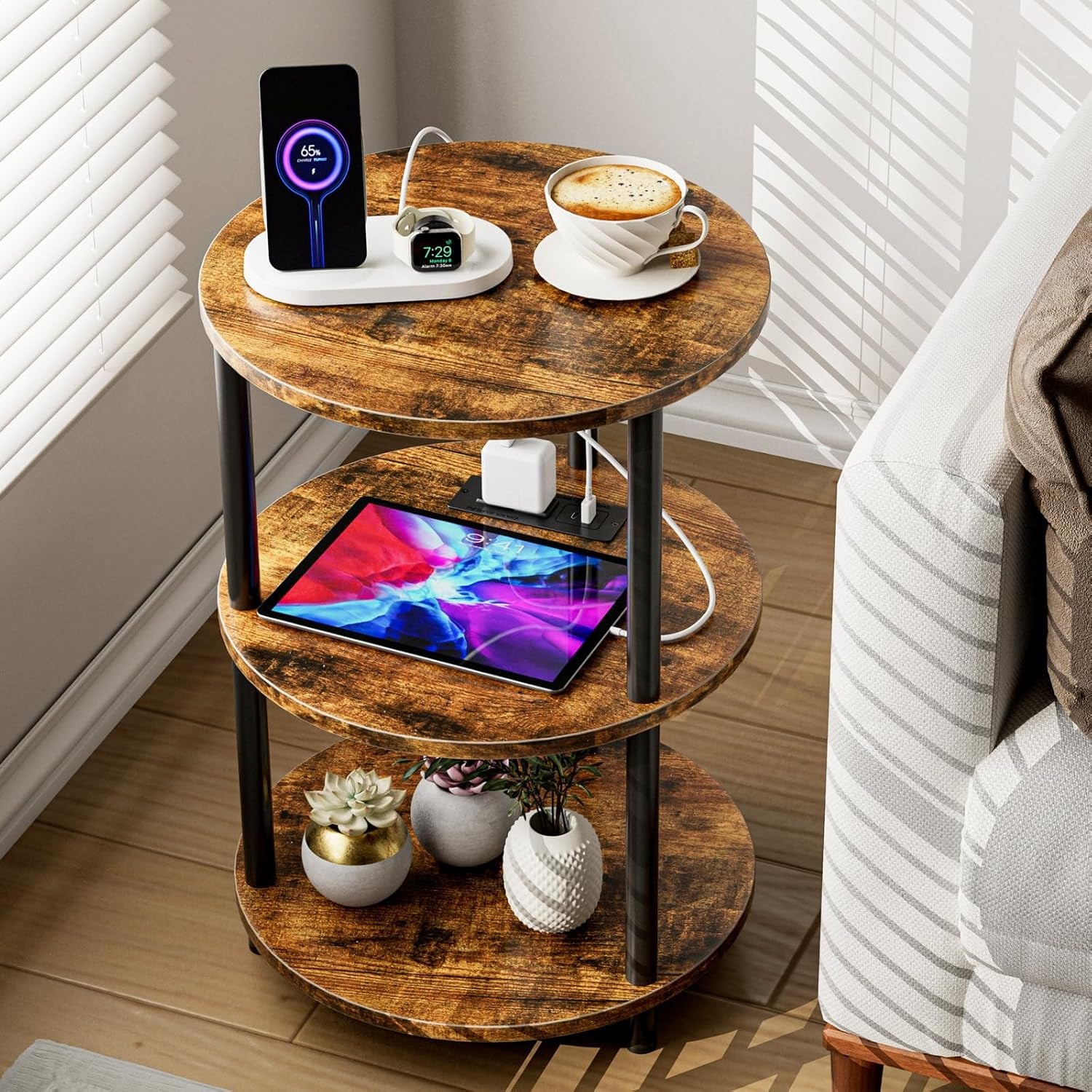 Rustic brown three-tier round table with a tablet on the middle shelf and small planters on the bottom shelf.