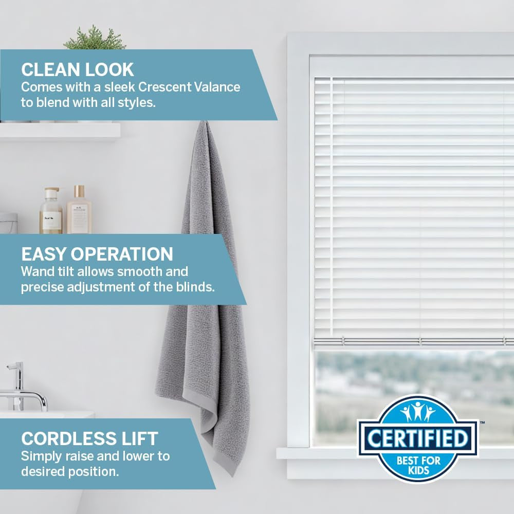 White faux wood blind in a bathroom setting showing crescent valance and wand tilt, partial window view.