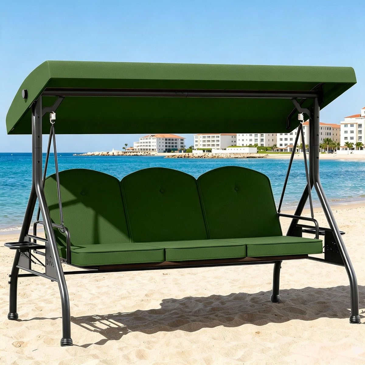 Green three-seat outdoor swing with canopy placed on beach sand with ocean in background.