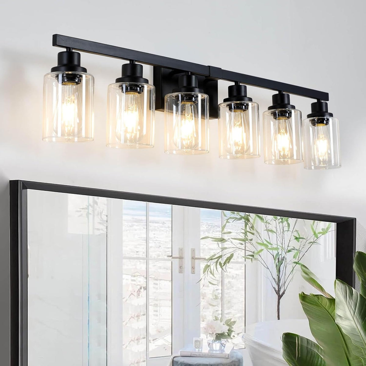 Five-light matte black vanity fixture with clear cylindrical shades mounted above a mirror.