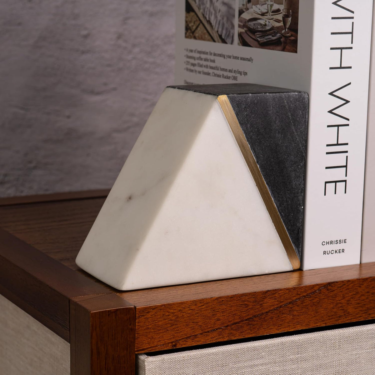 Close-up of one triangular marble bookend showing white base, dark gray top and a thin gold brass accent.