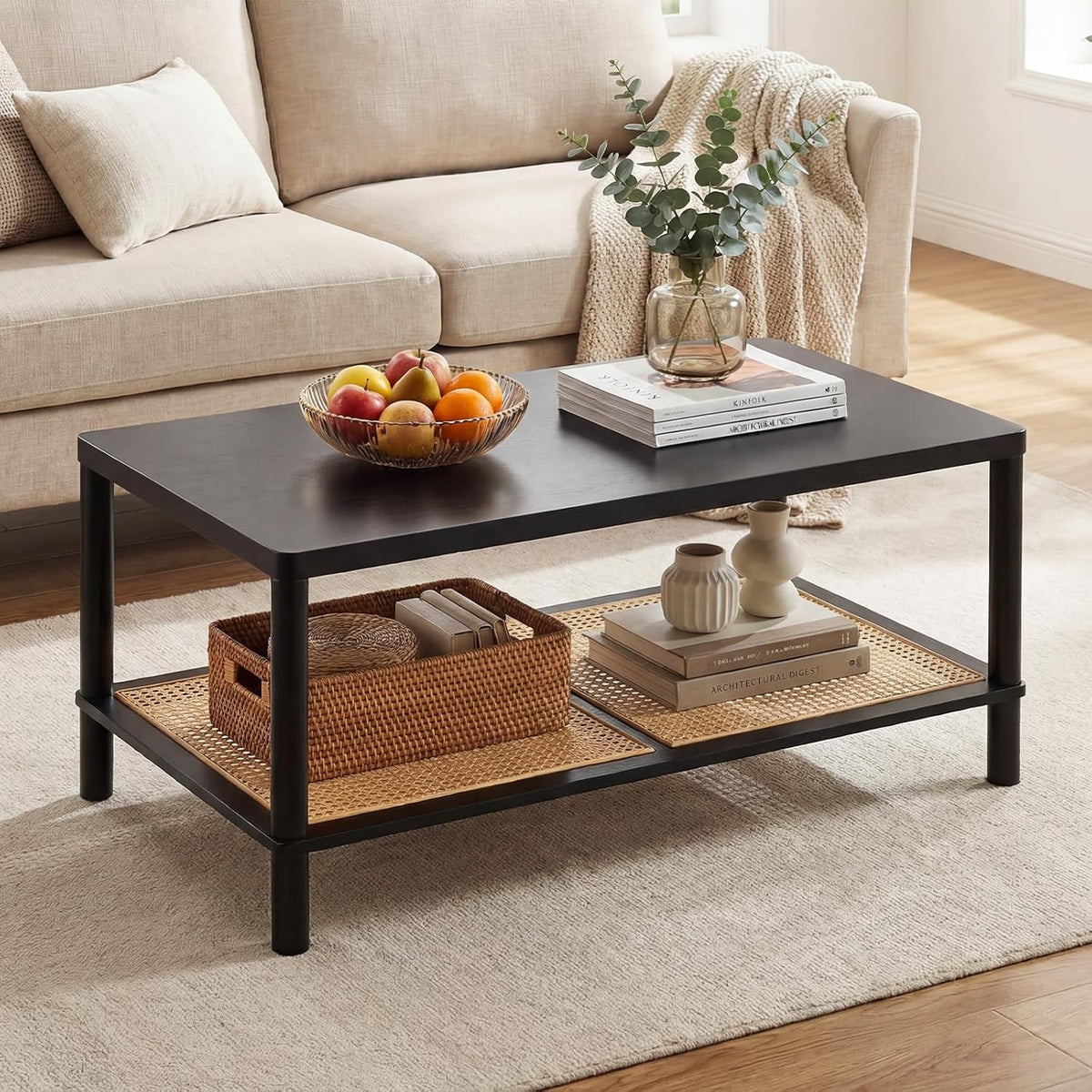 Rectangular black coffee table with rattan lower shelf and decorative bowl in front of a beige sofa