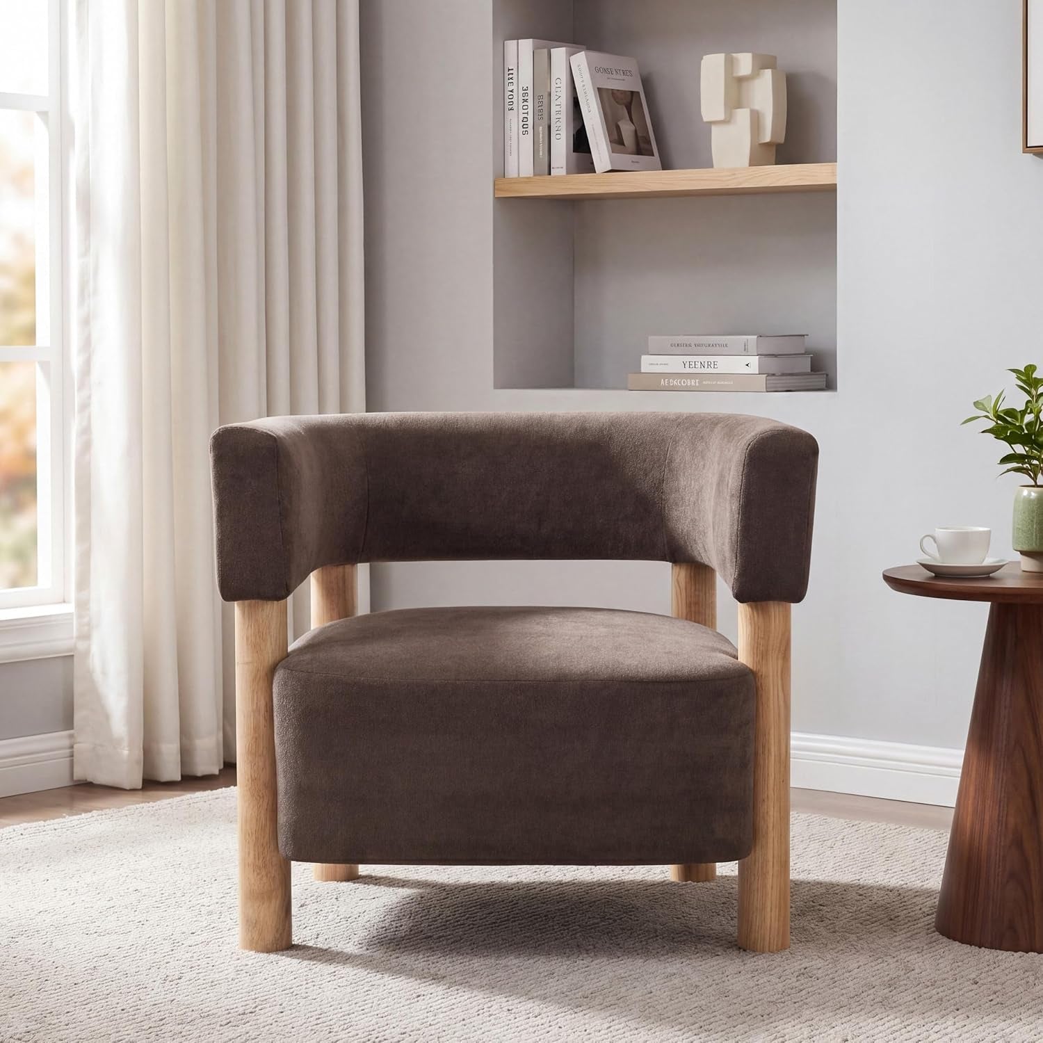 Low-profile accent chair in dark brown fabric with curved back and light wood legs beside a small round table